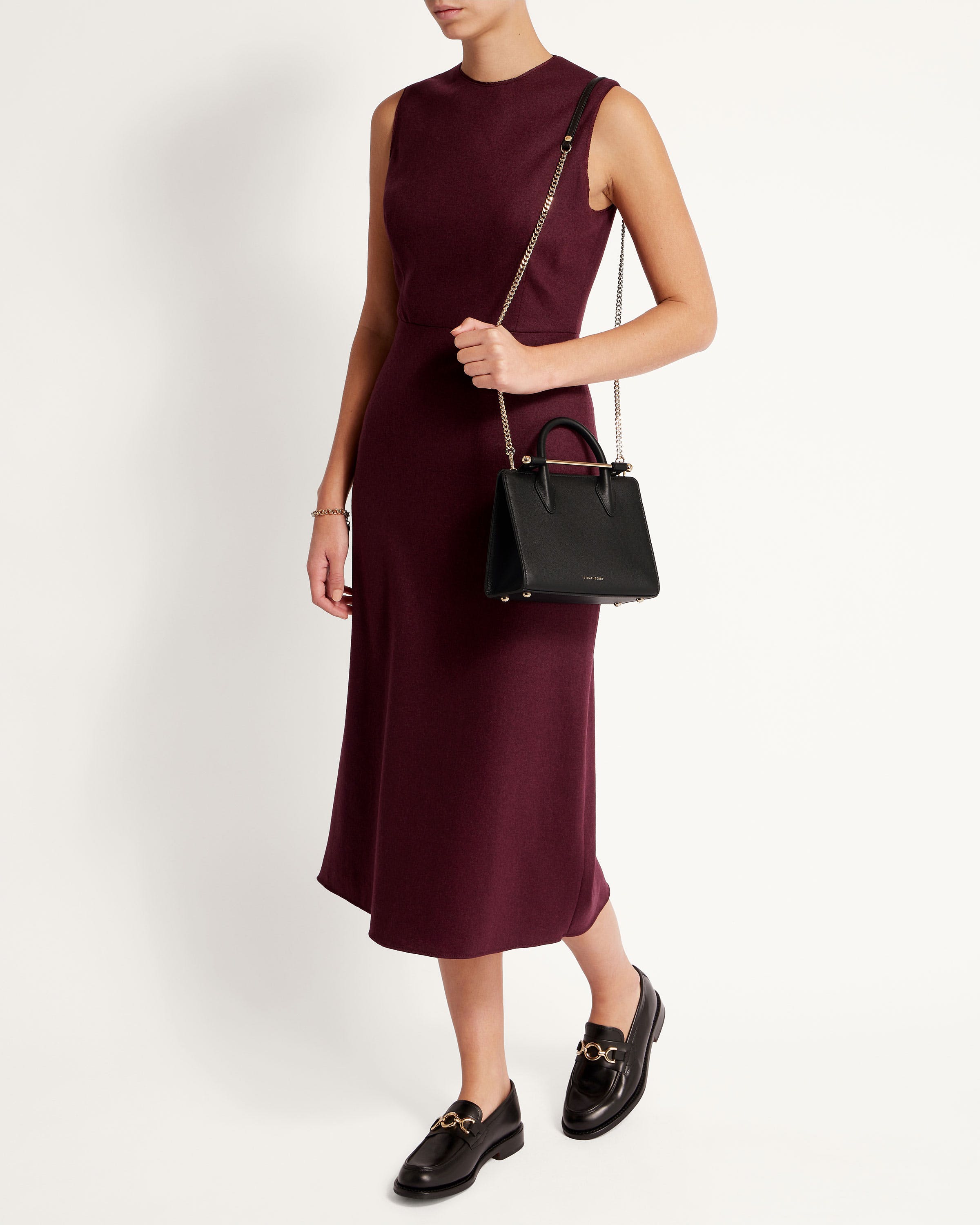 A woman in a maroon dress holding a black handbag