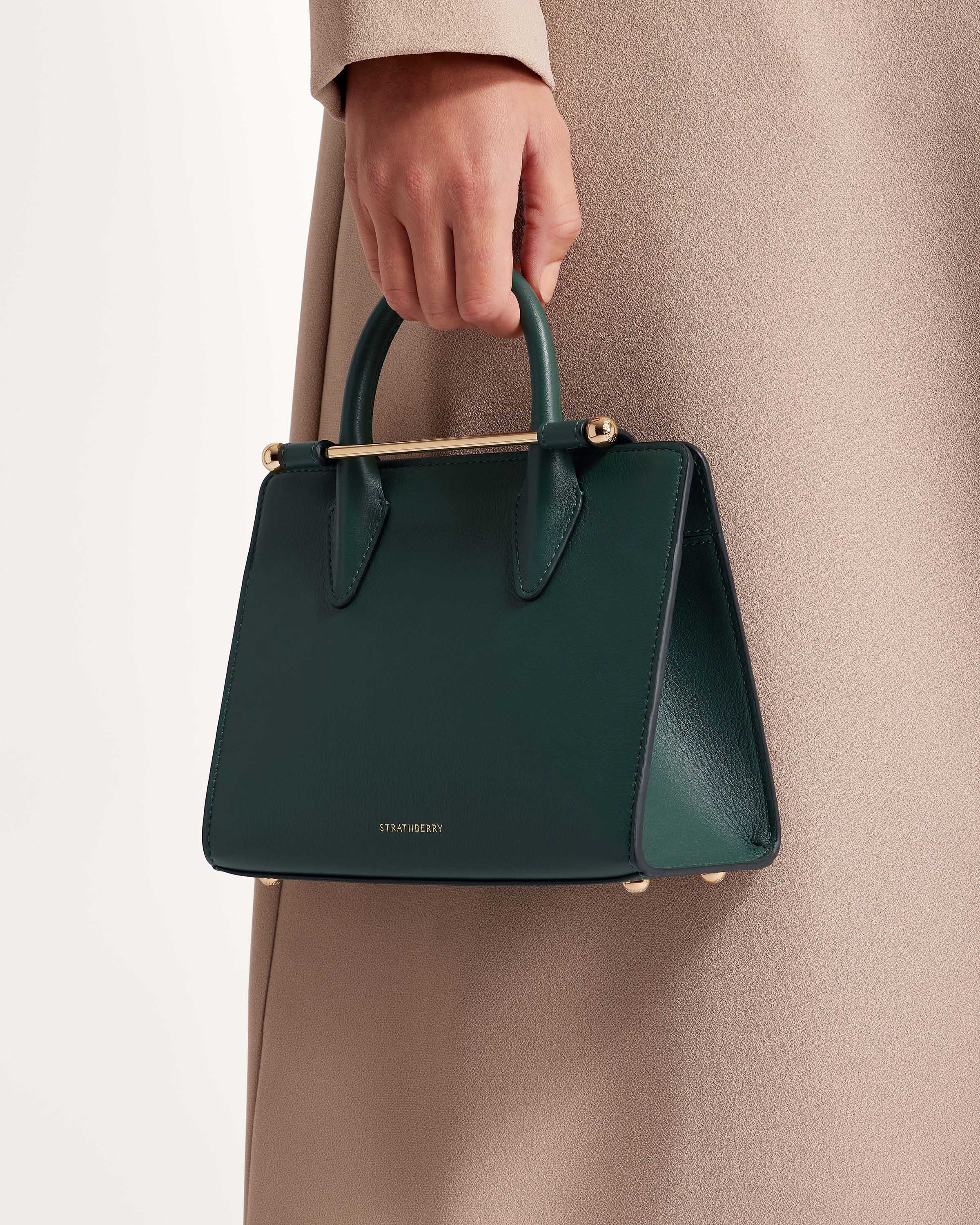 A woman's hand holding a green purse