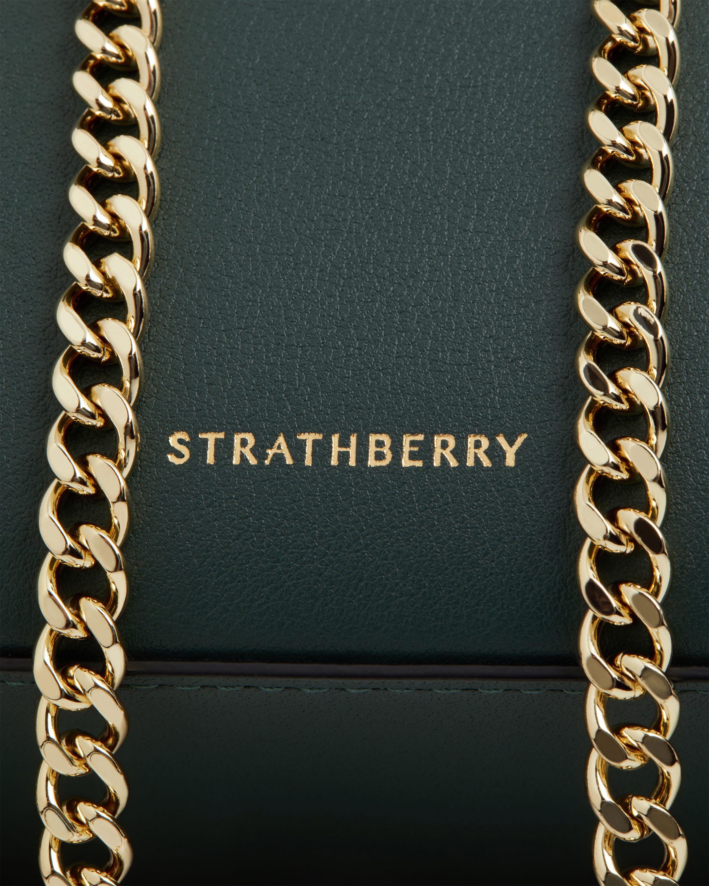 A close up of a gold chain on a green bag