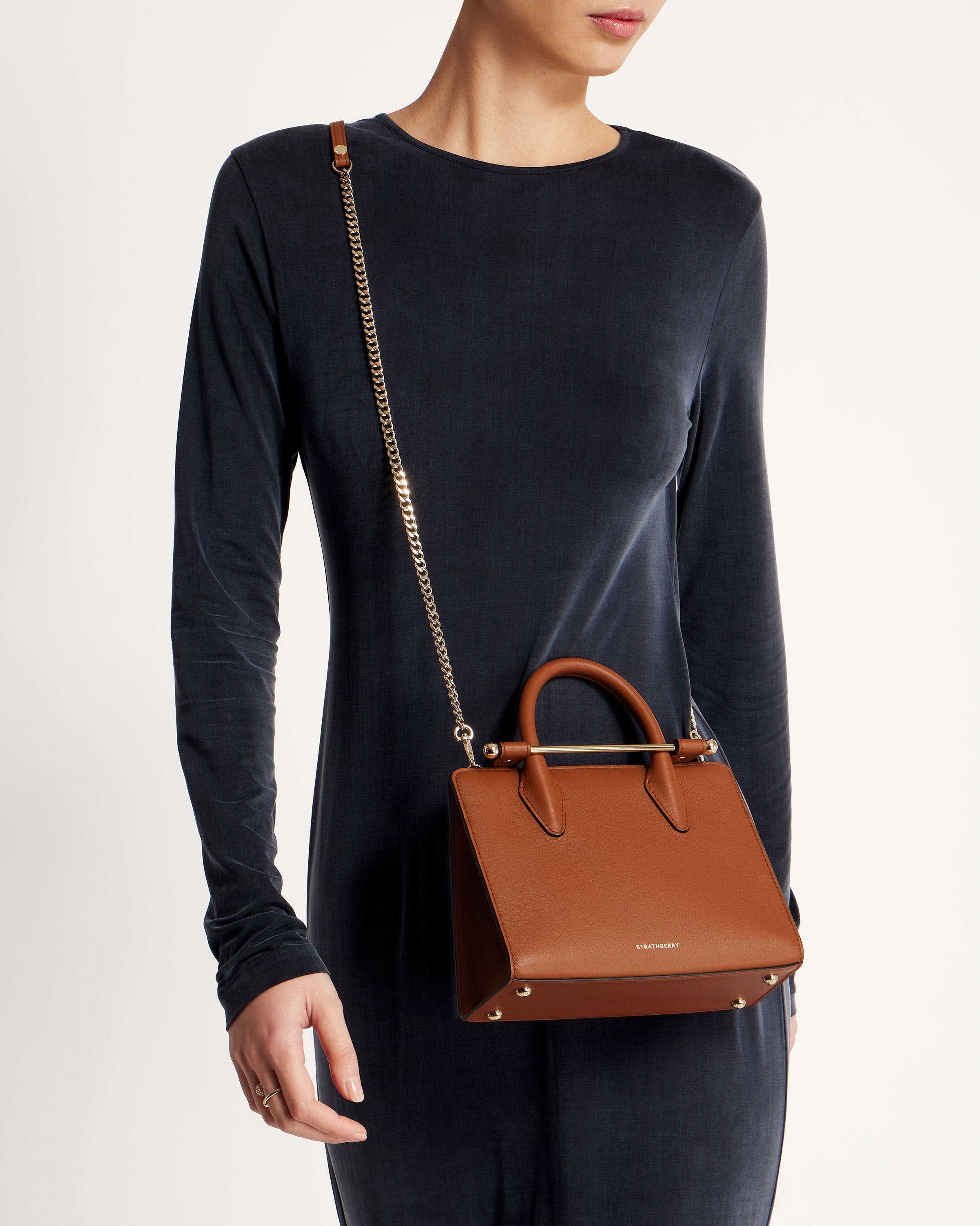 A woman is holding a brown handbag