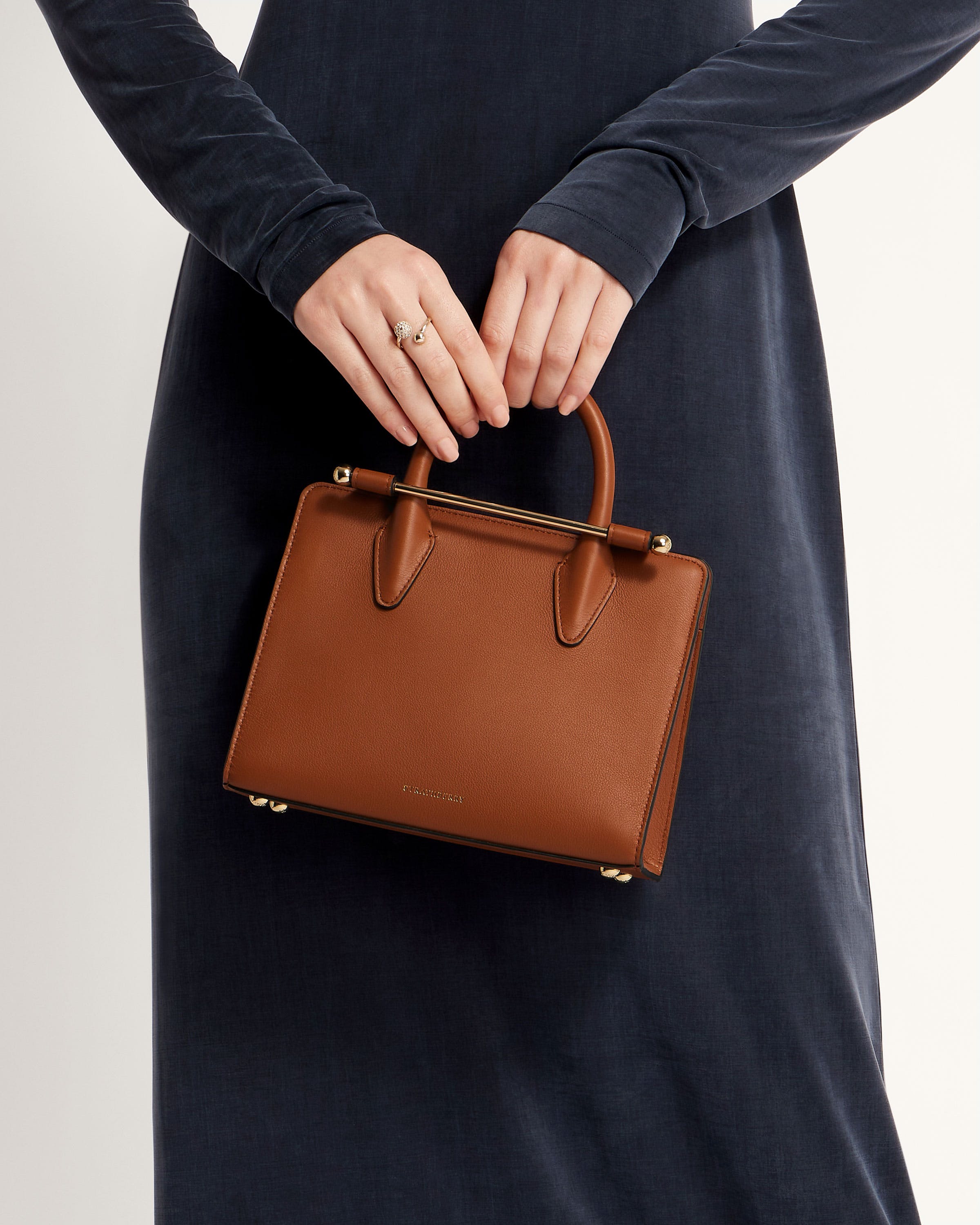 A woman in a black dress holding a brown purse