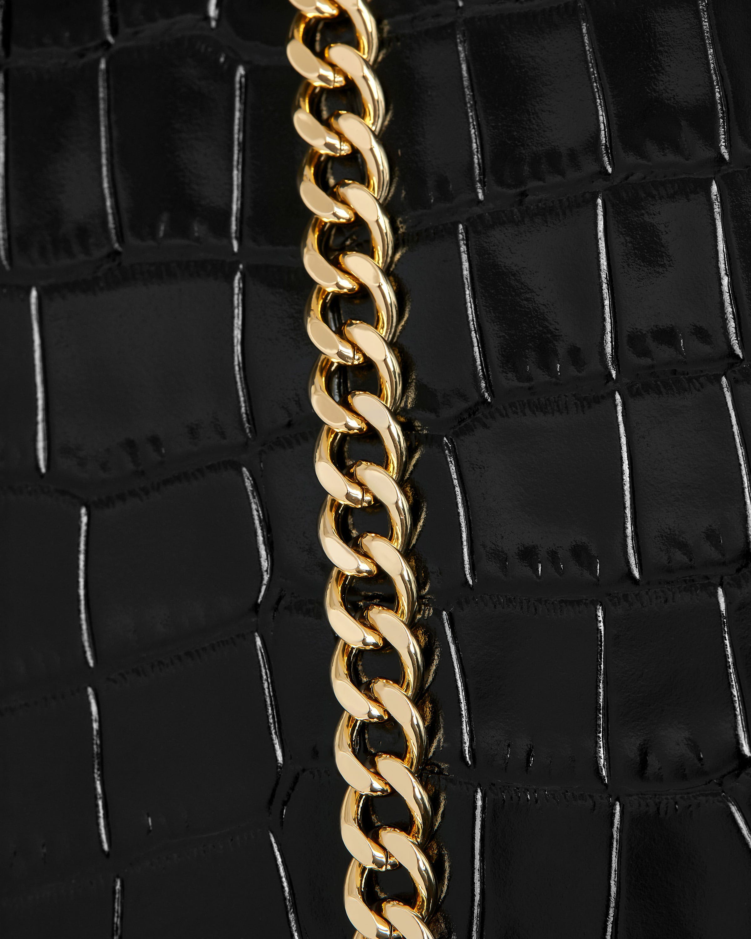 A close up of a gold chain on a black purse