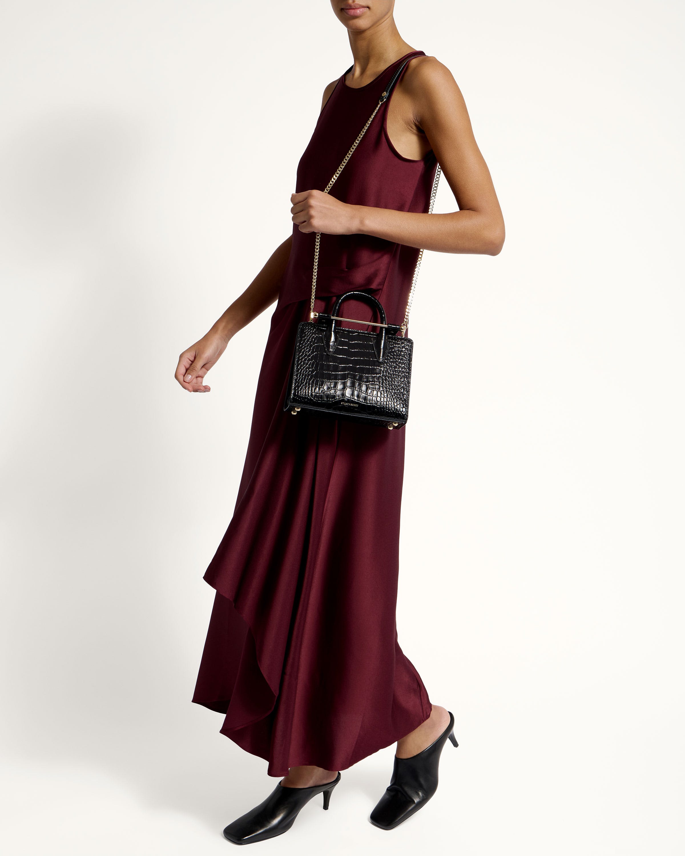 A woman in a maroon dress holding a black purse