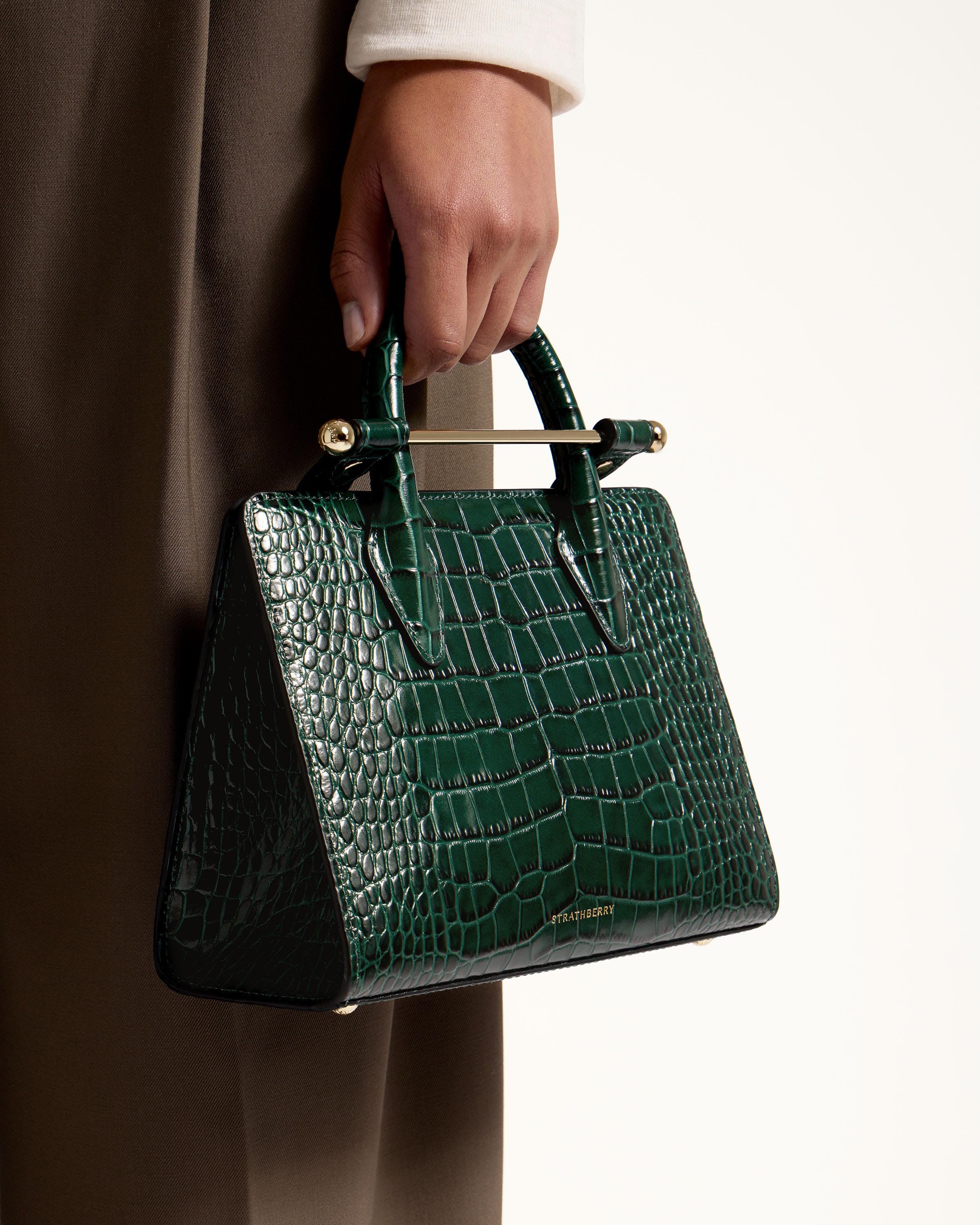 A person holding a green purse in their hand