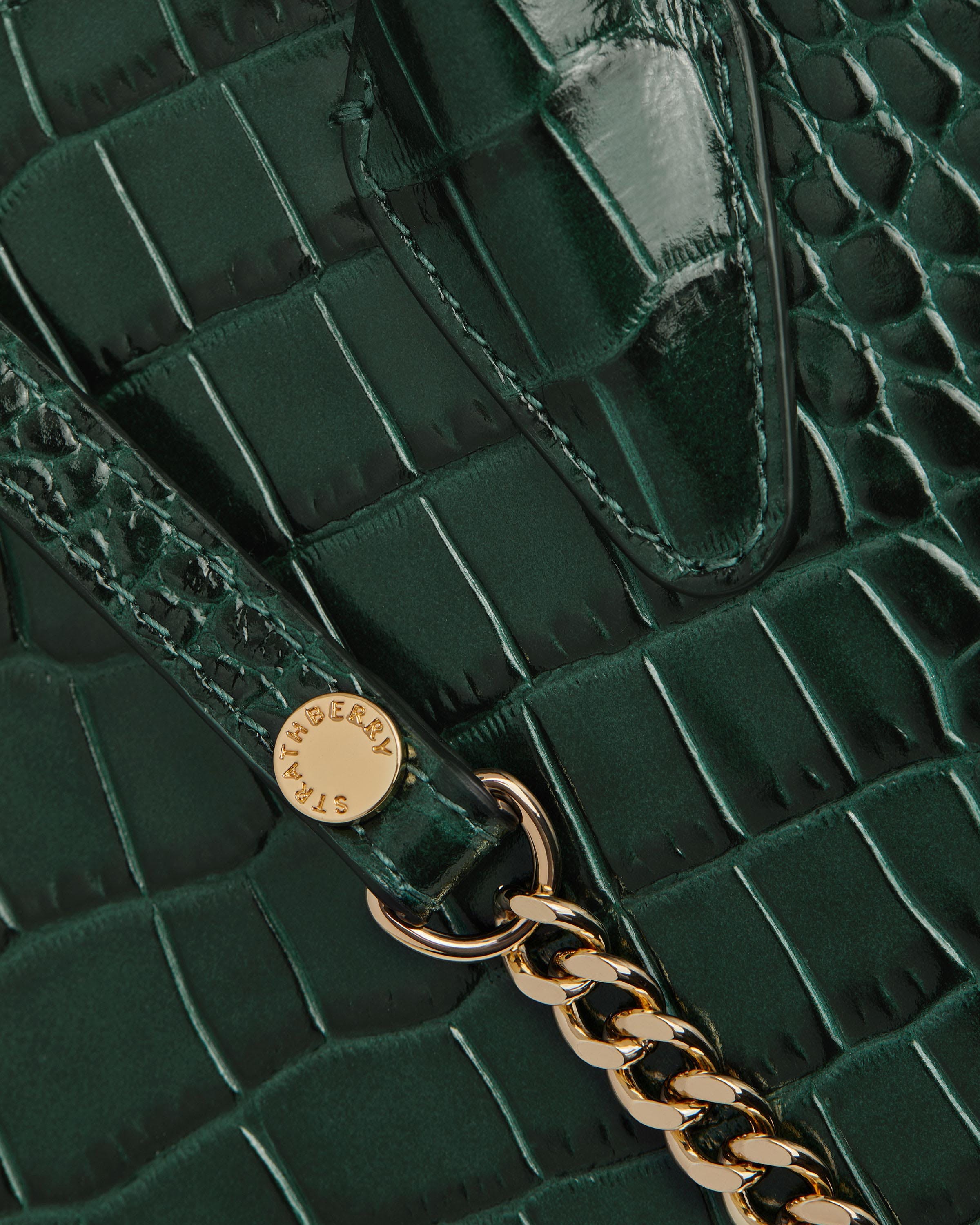 A close up of a green purse with a gold chain