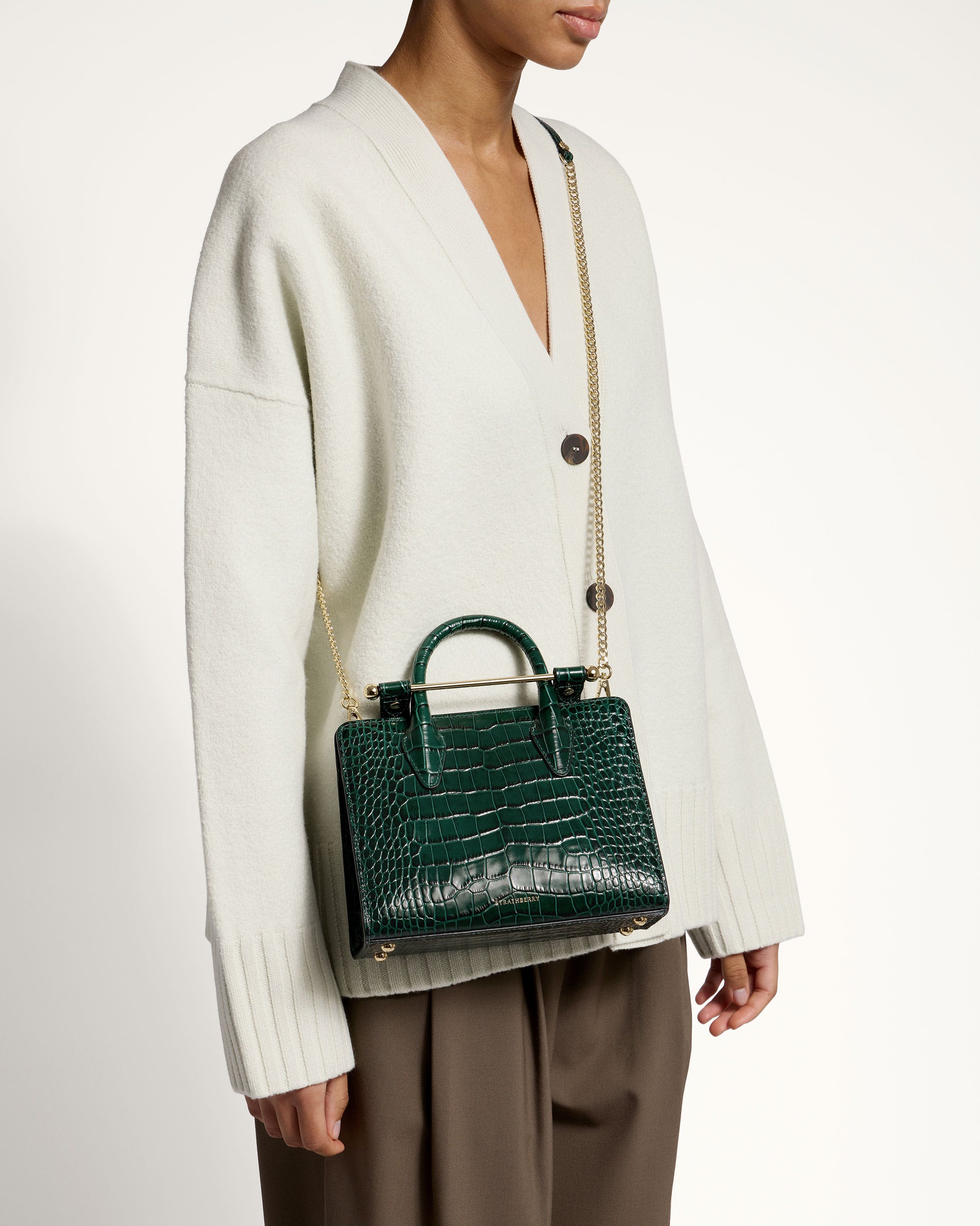 A woman in a white sweater holding a green handbag