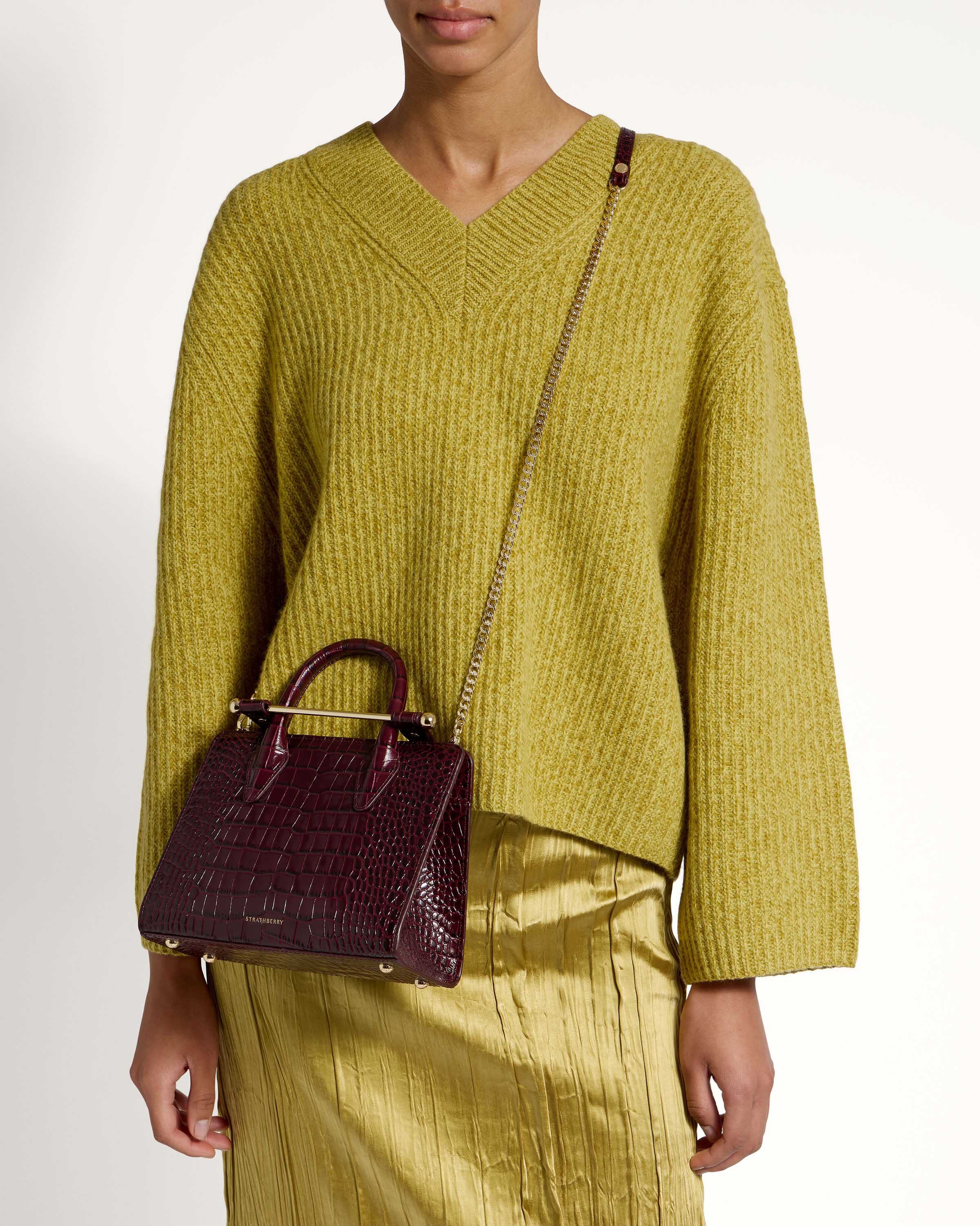 A woman wearing a green sweater and a brown purse