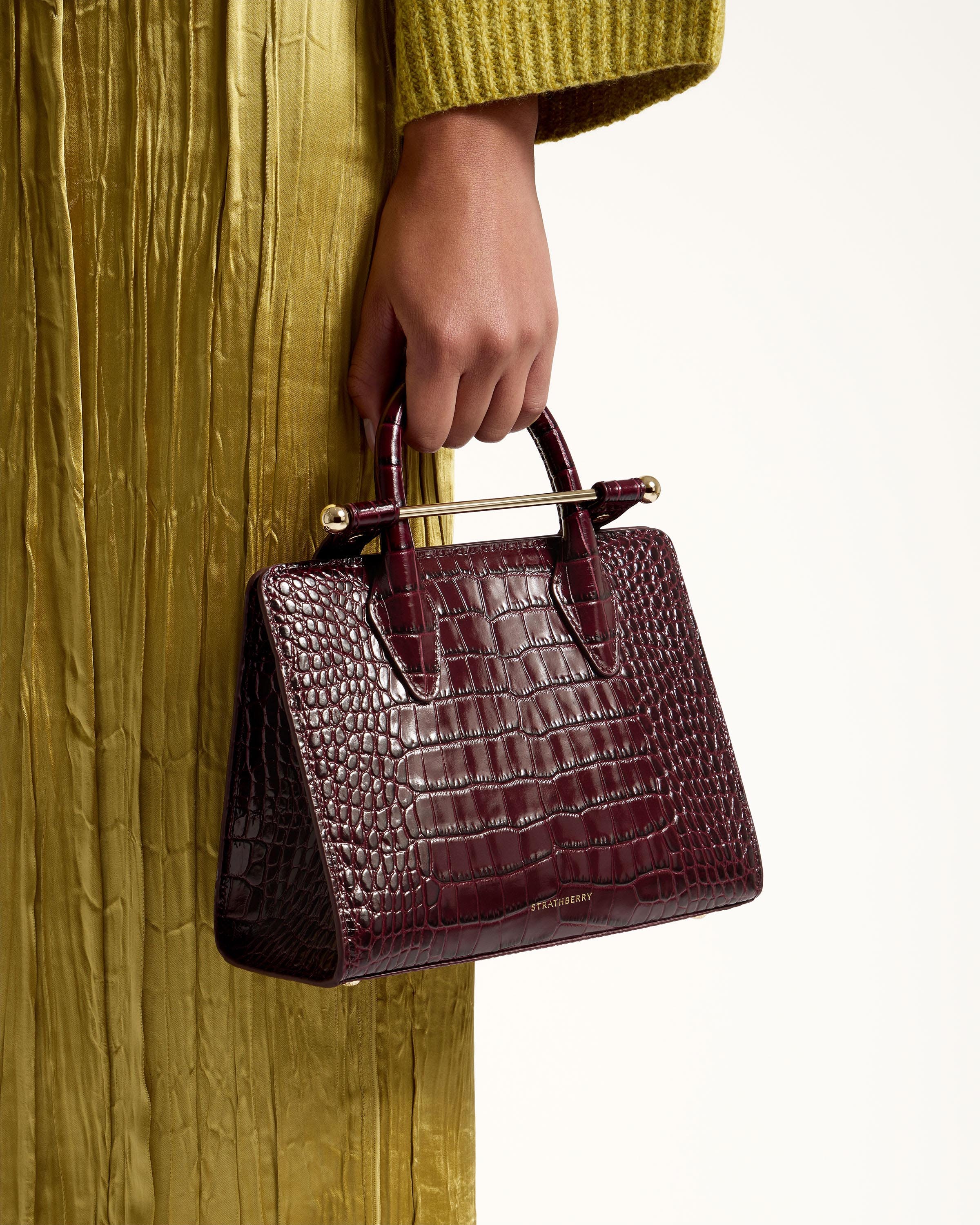 A woman in a green dress holding a brown purse