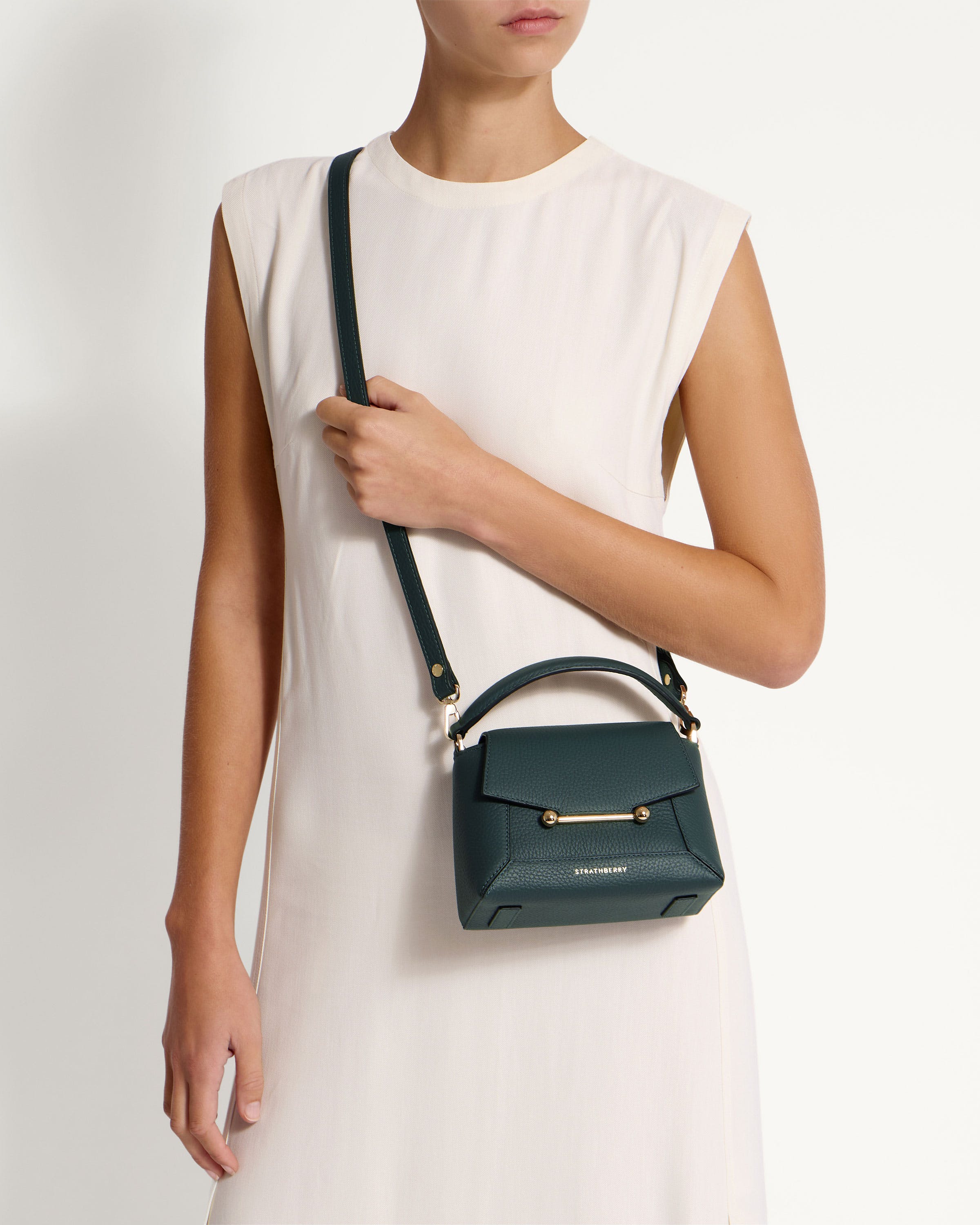 A woman in a white dress holding a green handbag