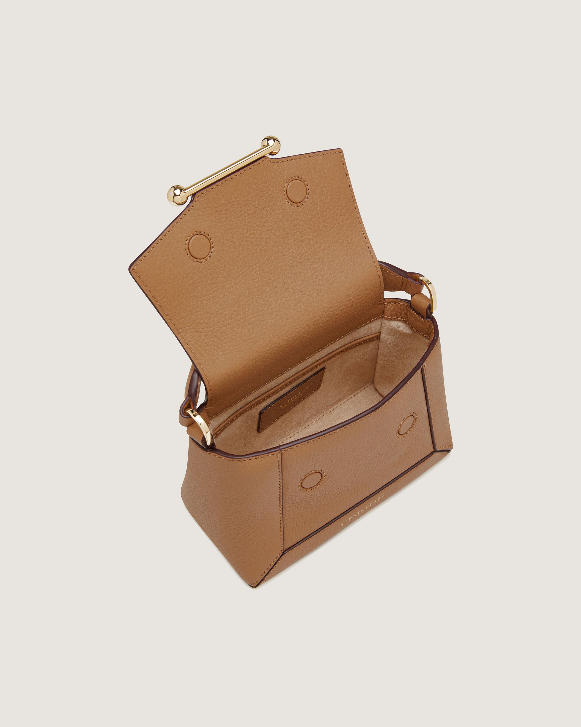 A tan leather purse with a gold handle