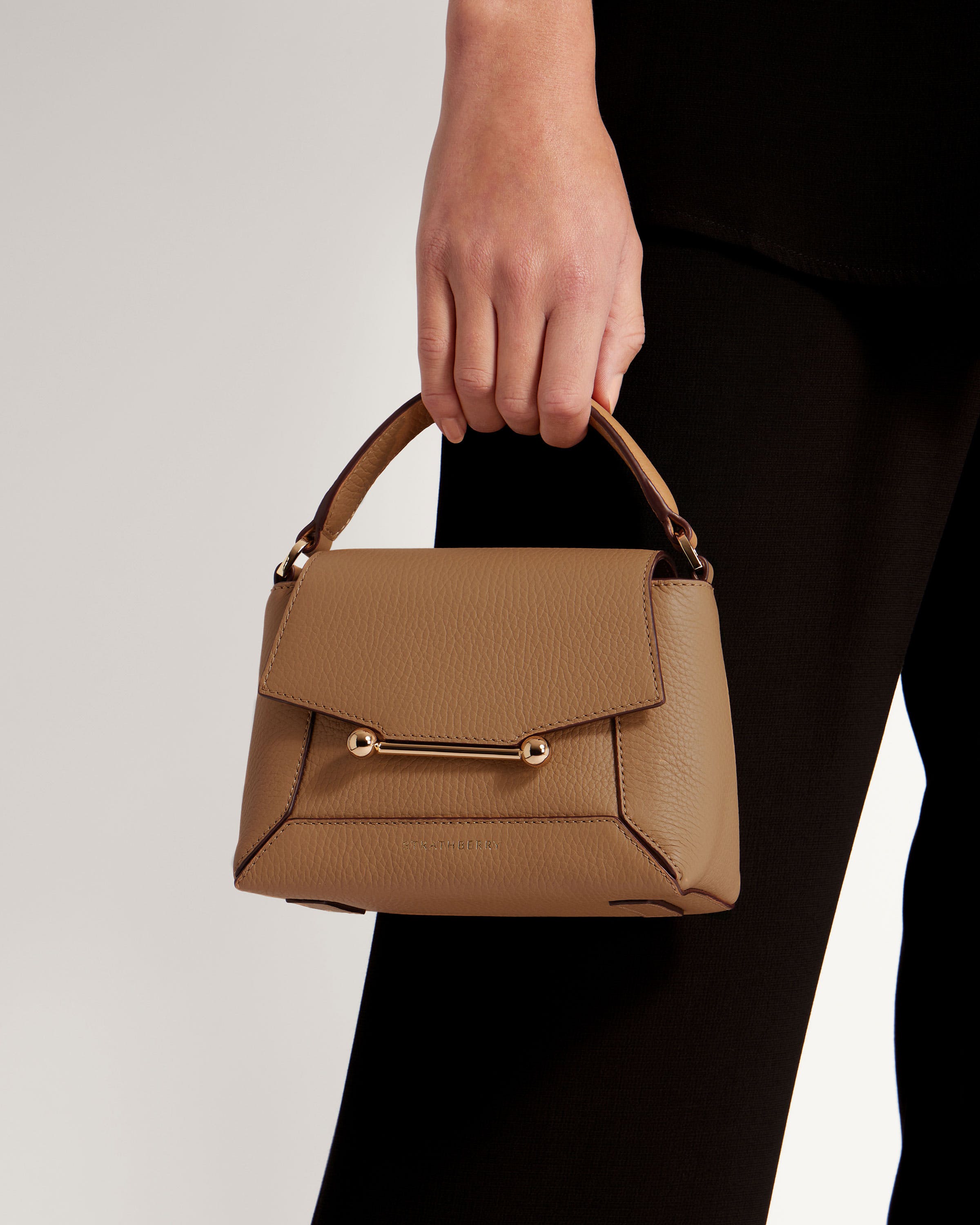 A woman's hand holding a brown purse