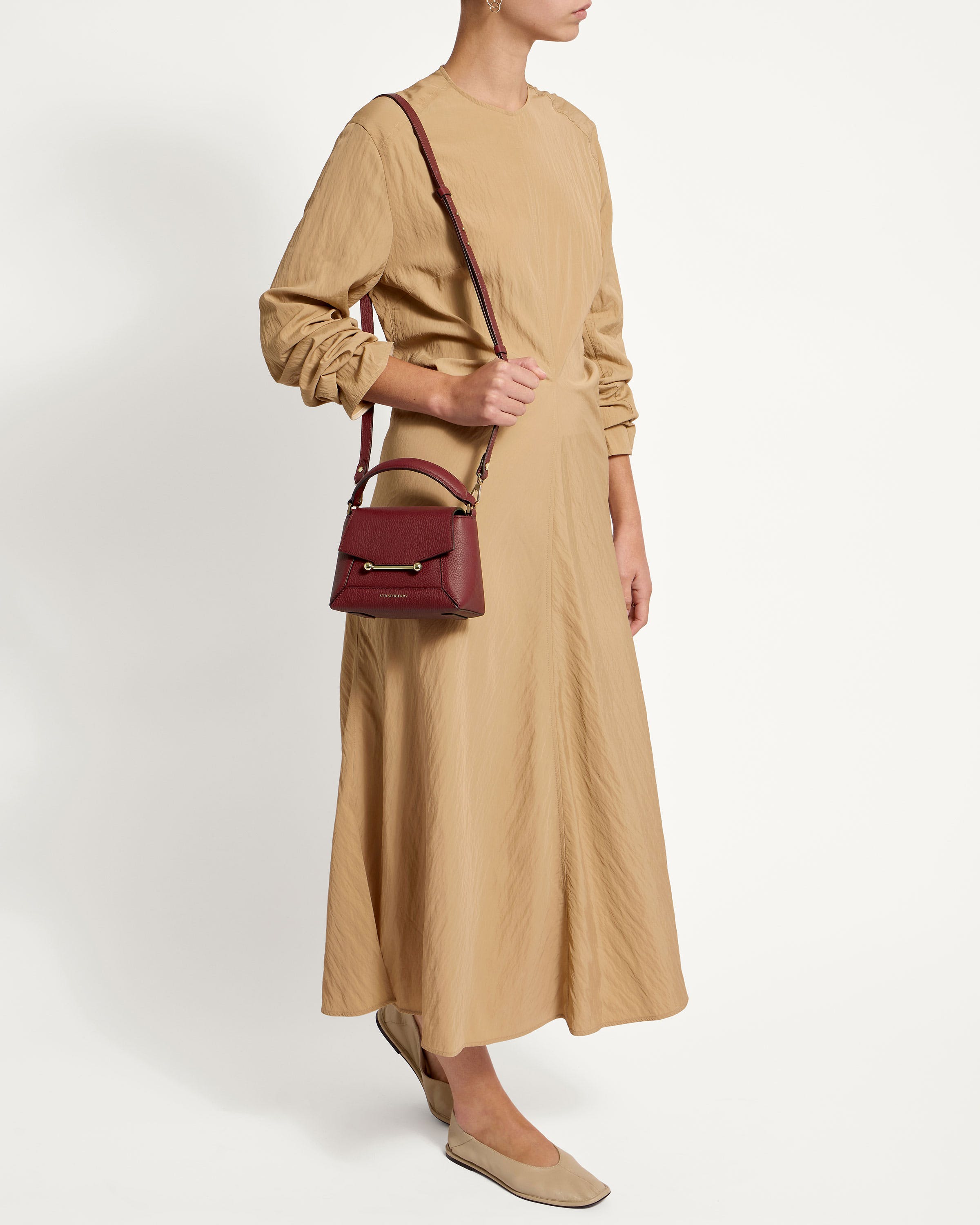 A woman in a tan dress holding a brown bag