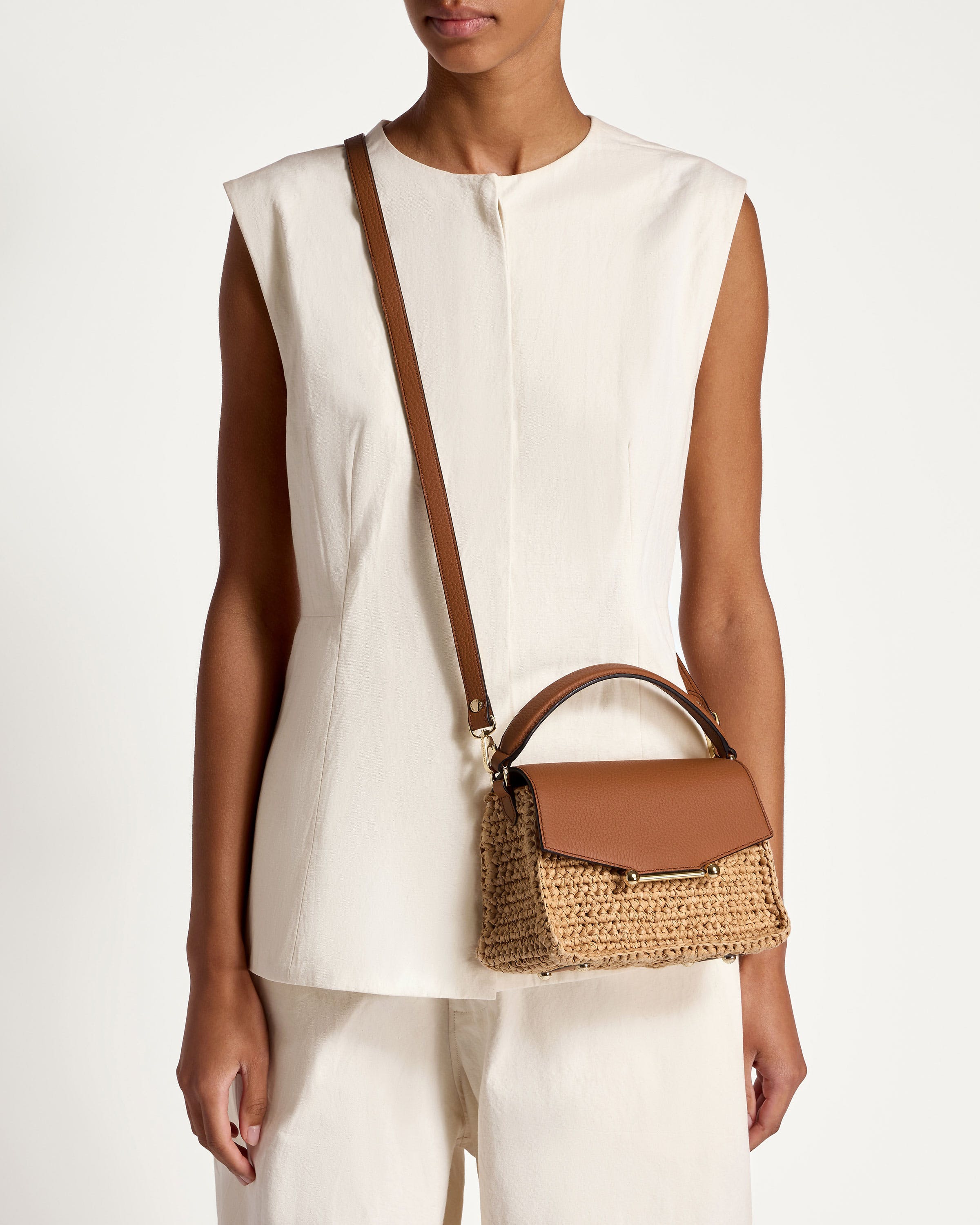 A woman wearing a white top holding a brown purse