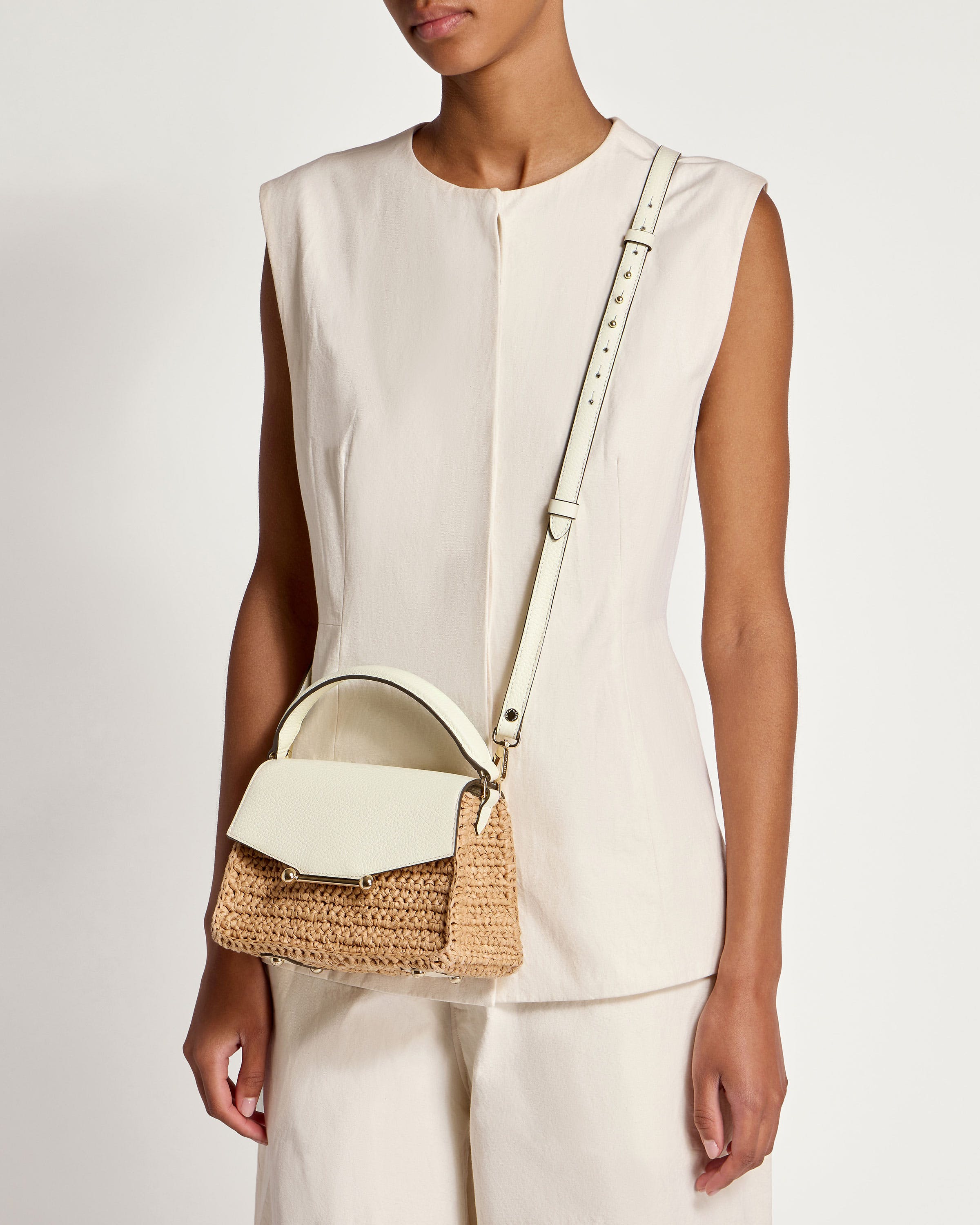 A woman wearing a white top and a straw bag