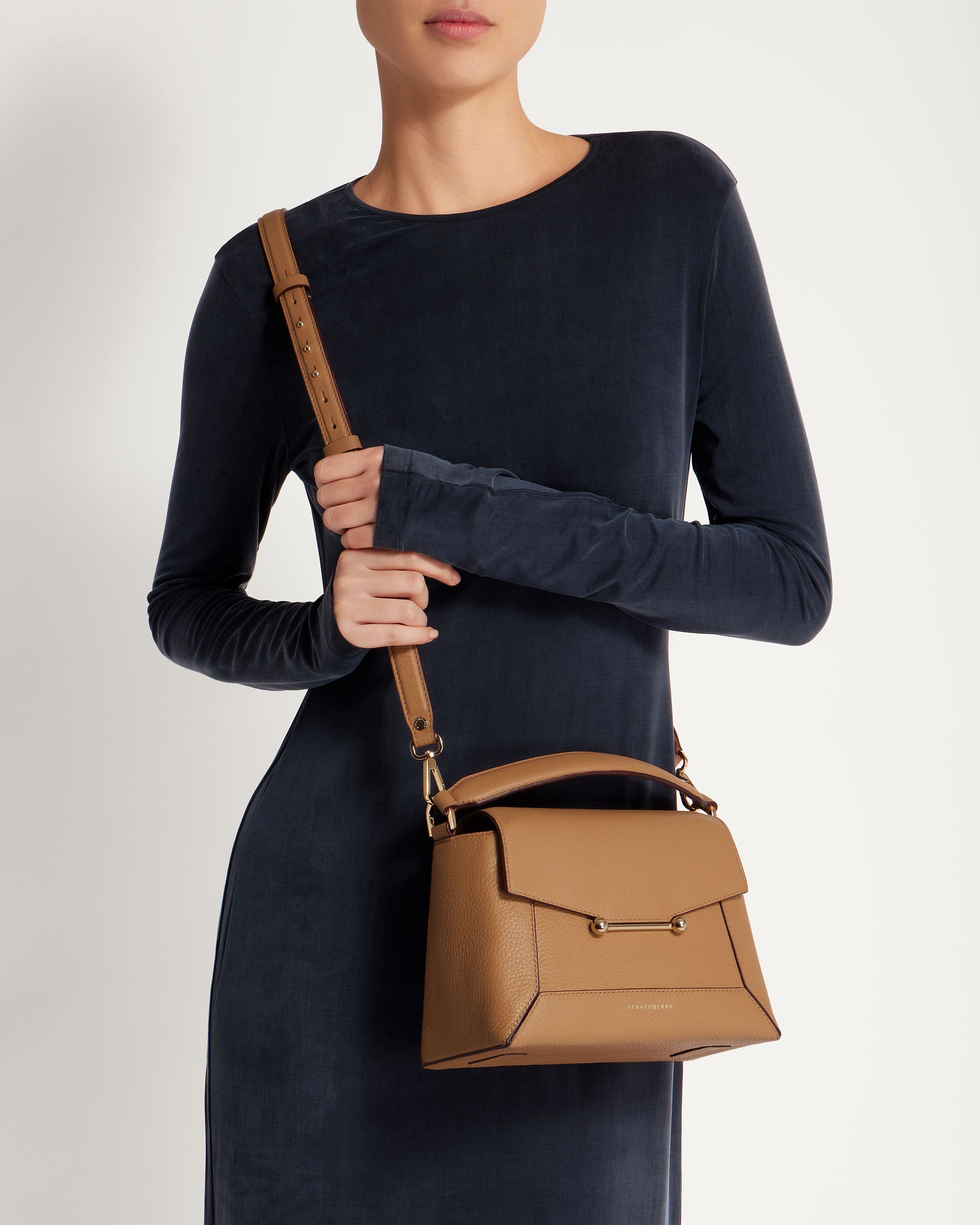 A woman is holding a brown handbag