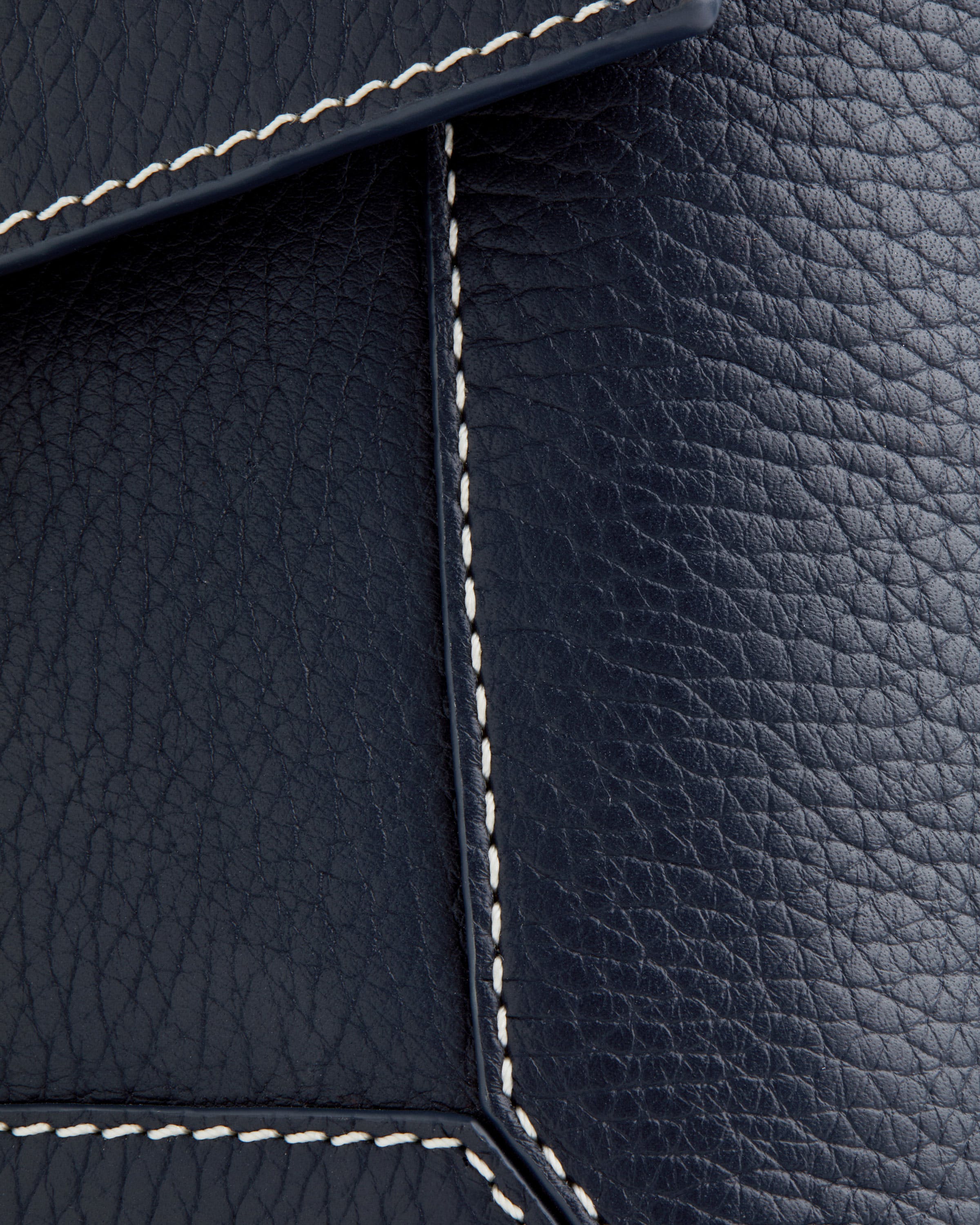 A close up of a black leather material with white stitching