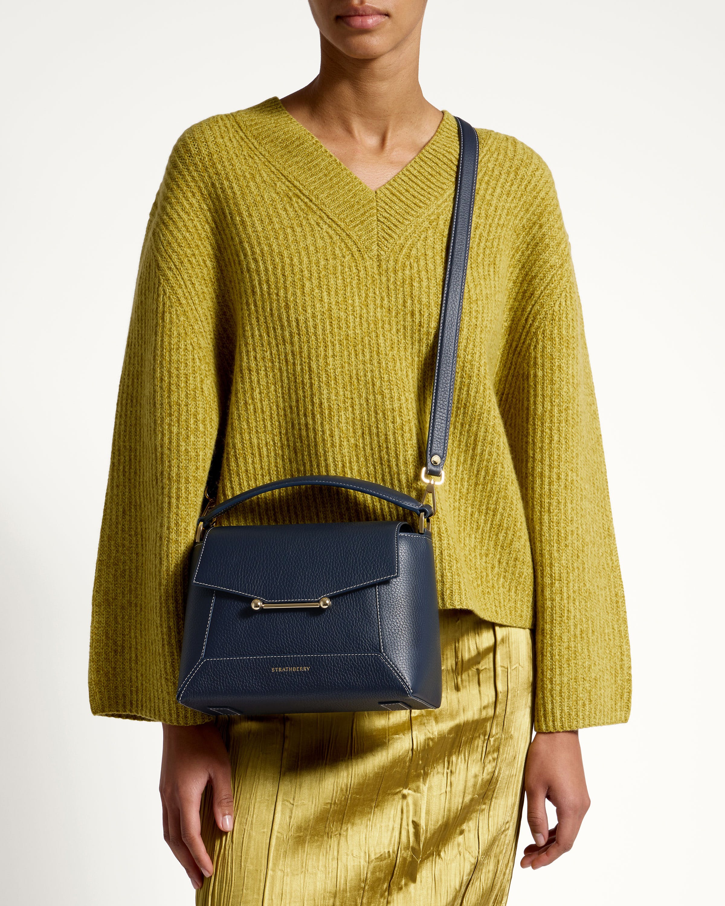 A woman in a yellow sweater holding a blue purse