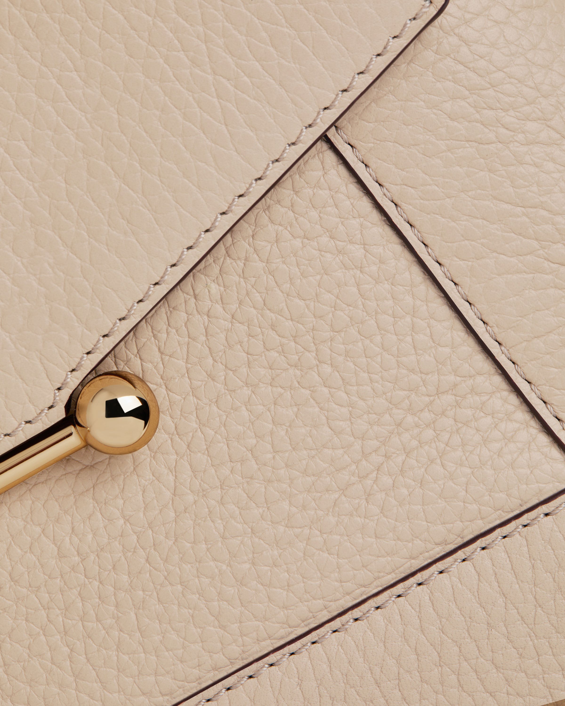 A close up of a white purse with a gold handle