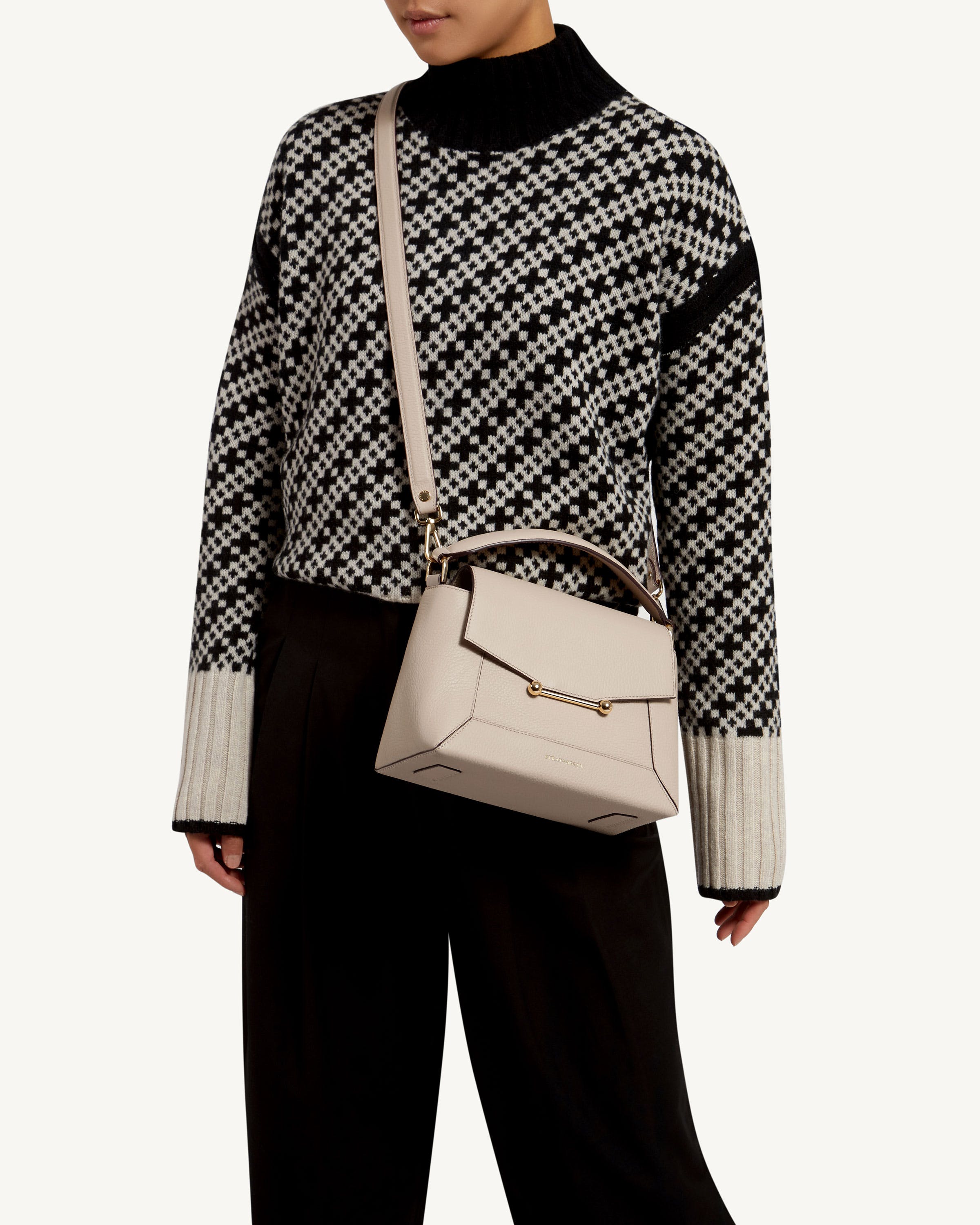 A woman in a black and white sweater holding a white purse