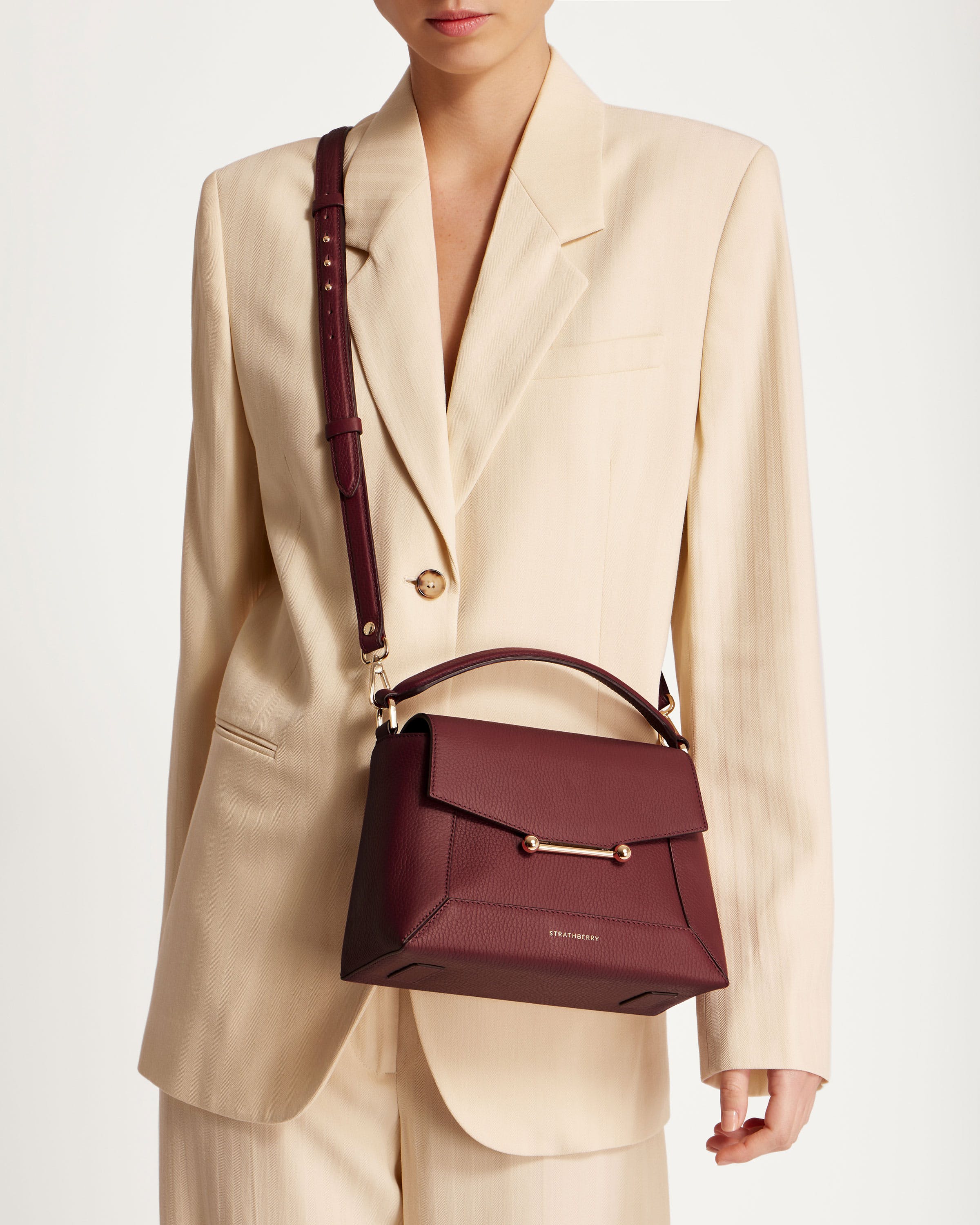 A woman in a suit holding a burgundy purse