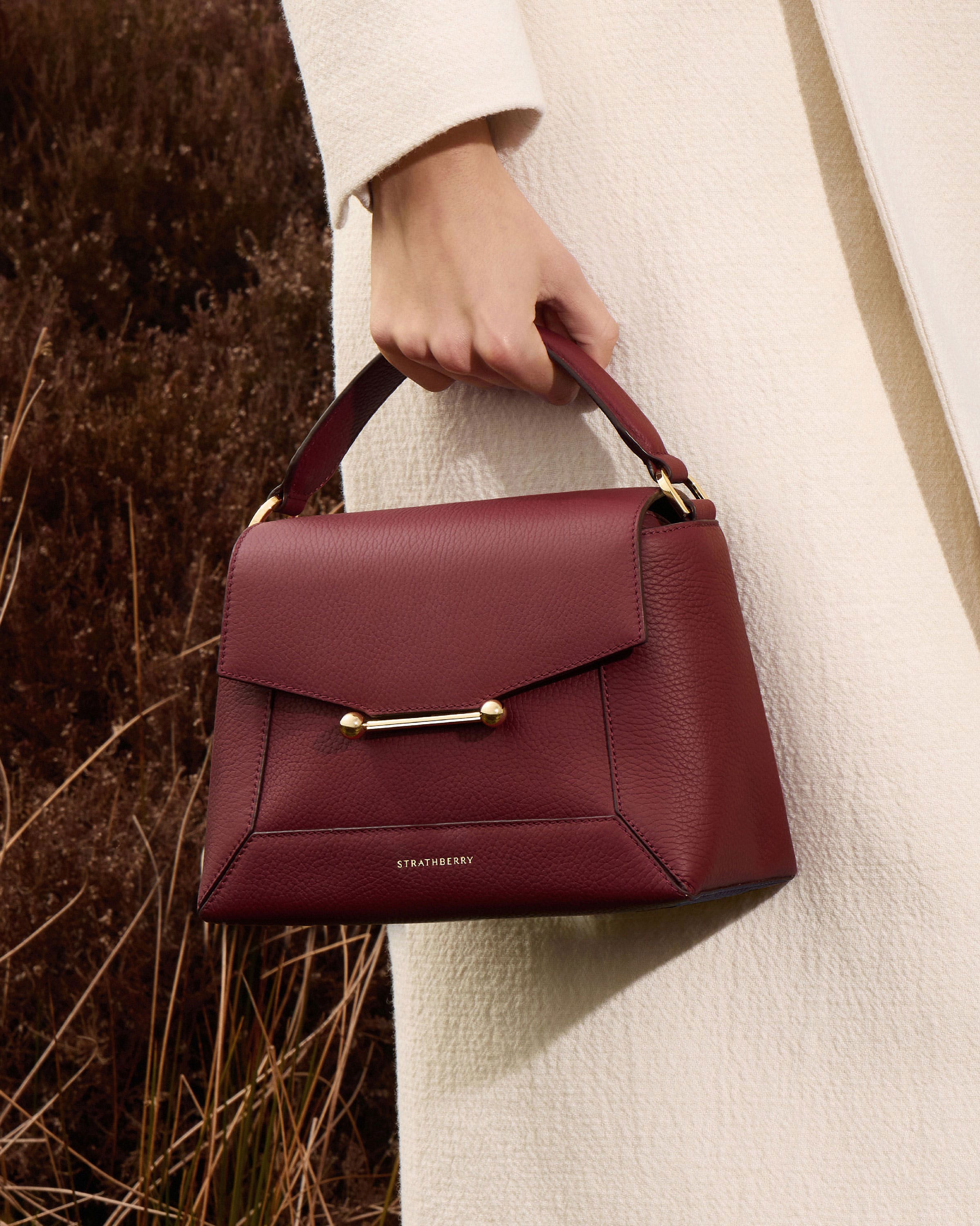 A woman holding a red purse in her hand