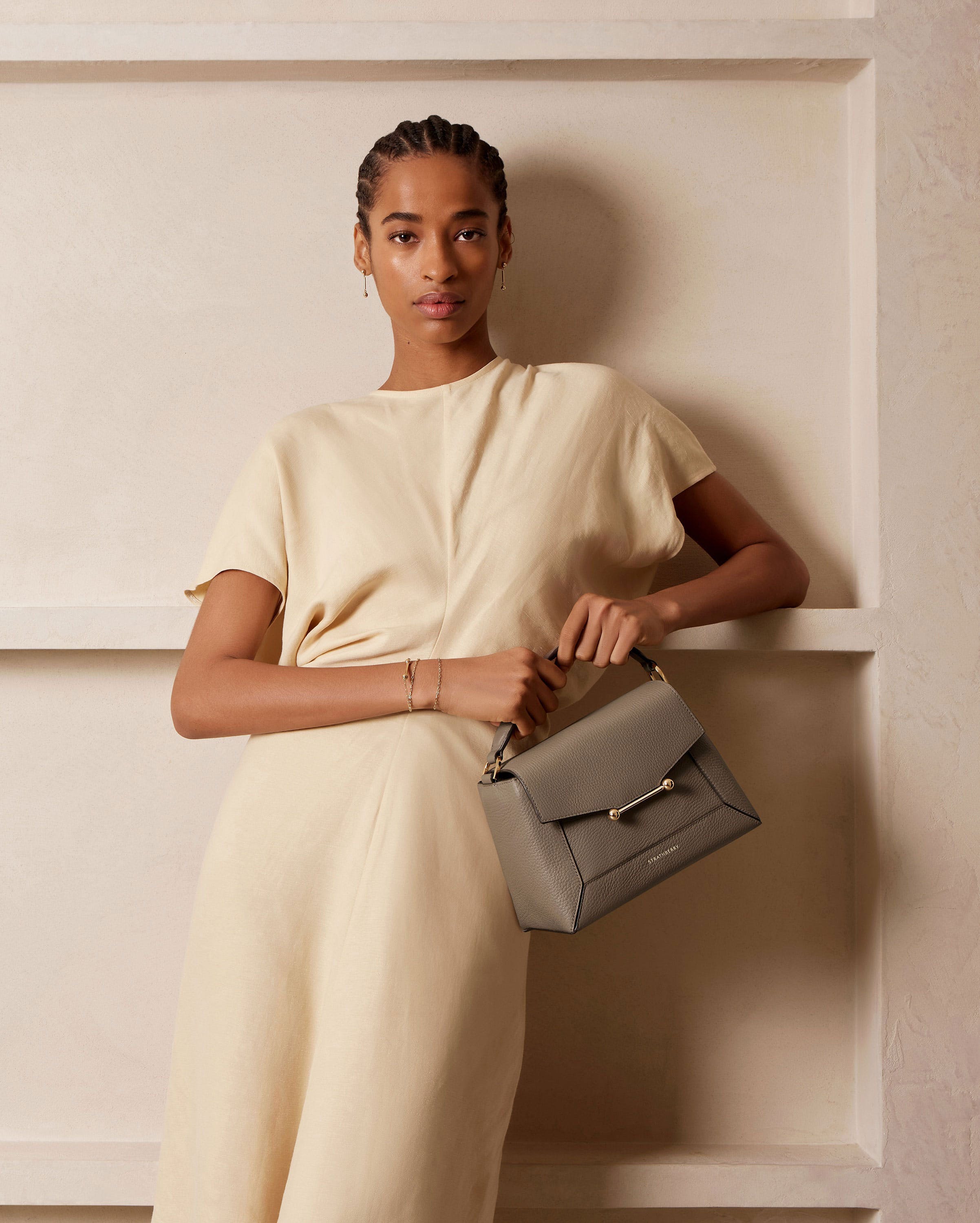 A woman in a white dress holding a gray purse