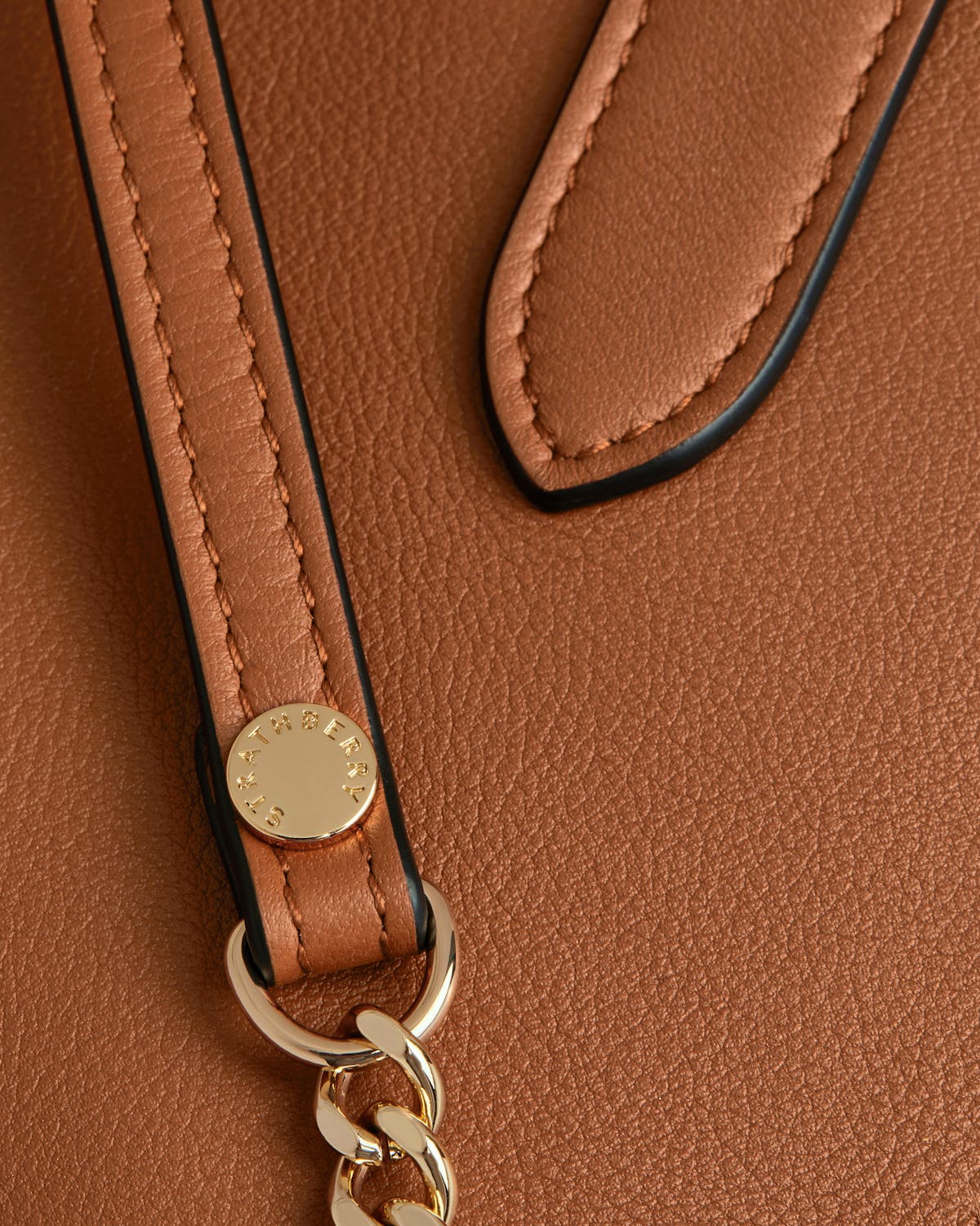 A close up of a brown purse with a key chain