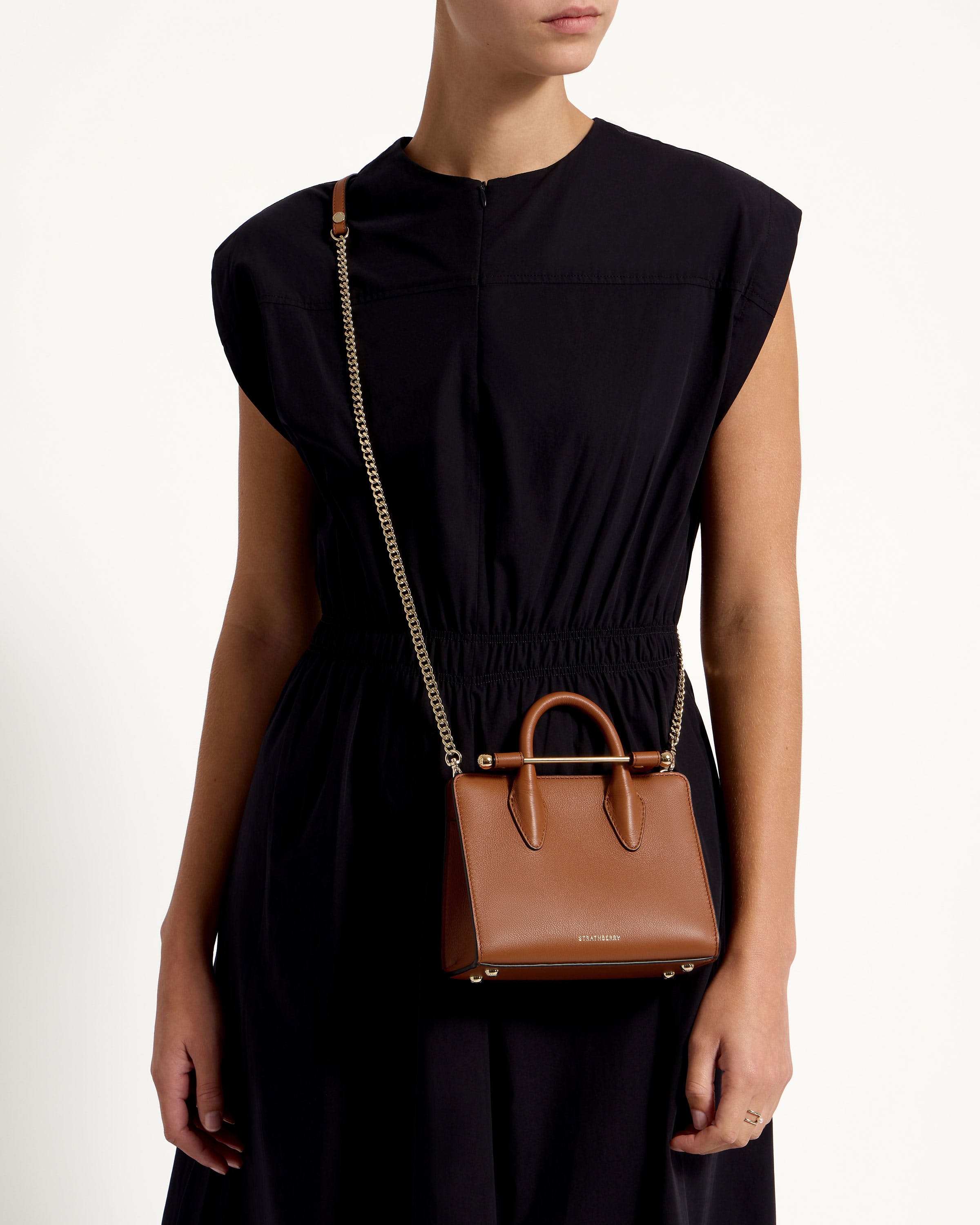 A woman in a black dress holding a brown handbag