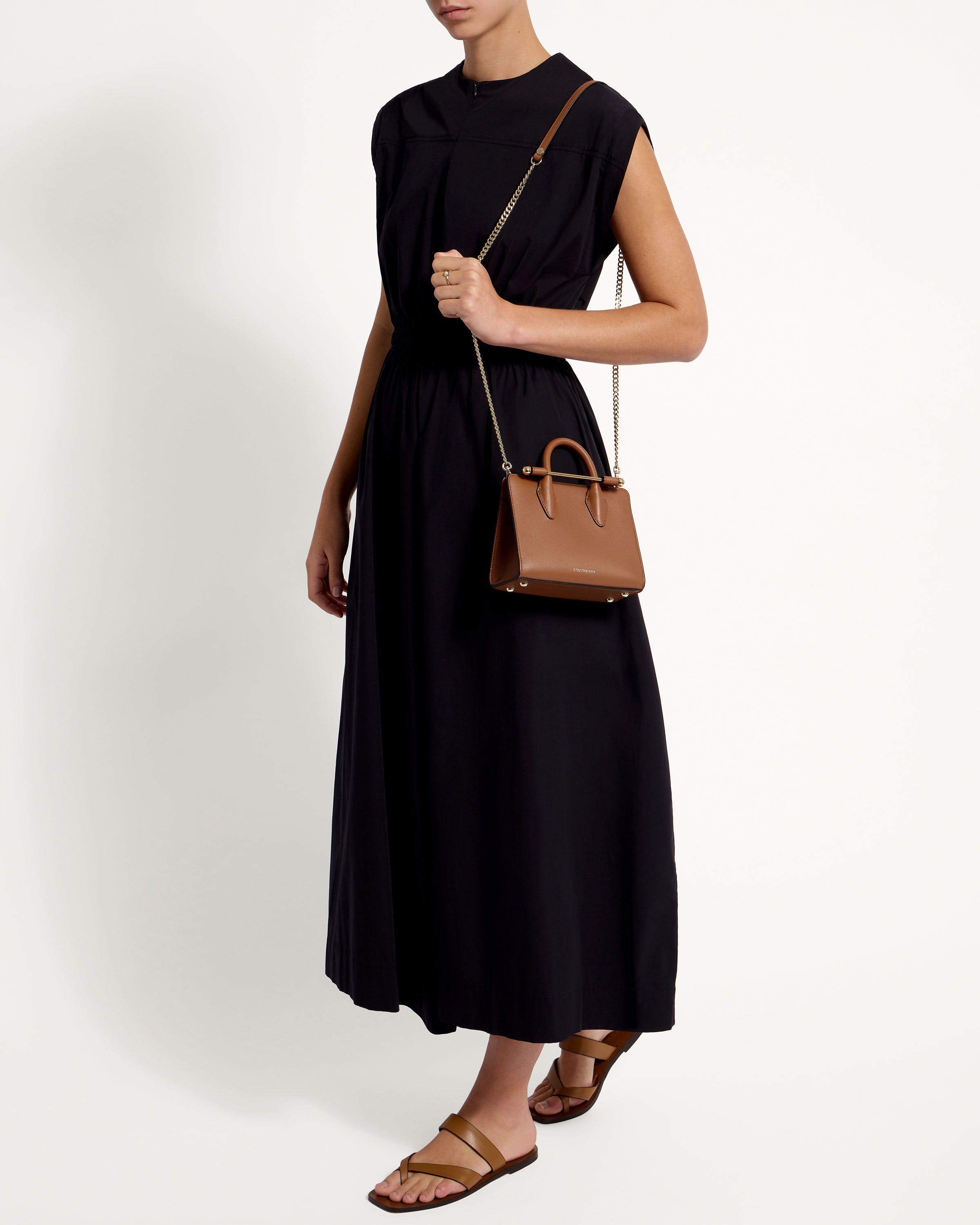 A woman in a black dress holding a brown handbag