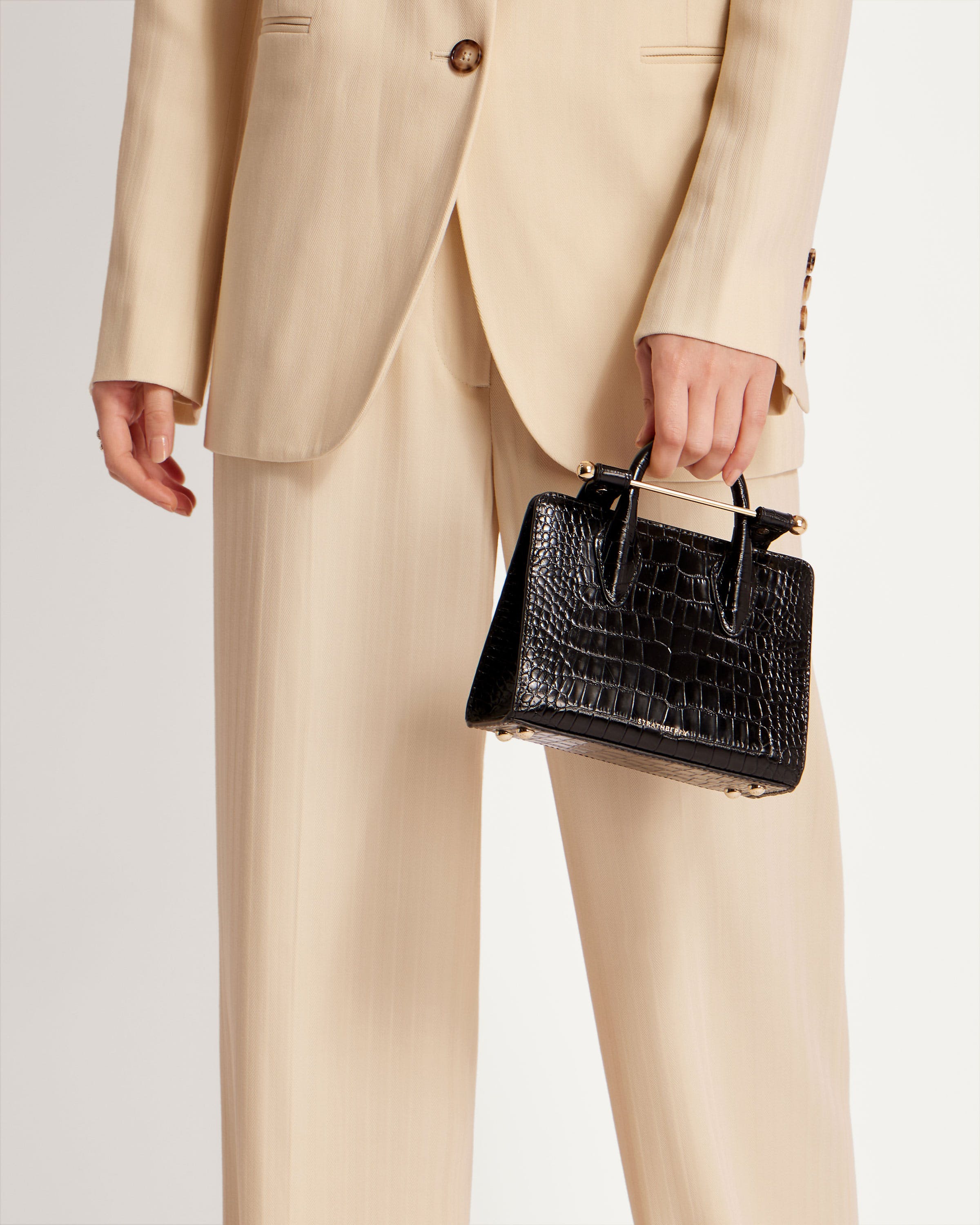 A person in a suit holding a black purse