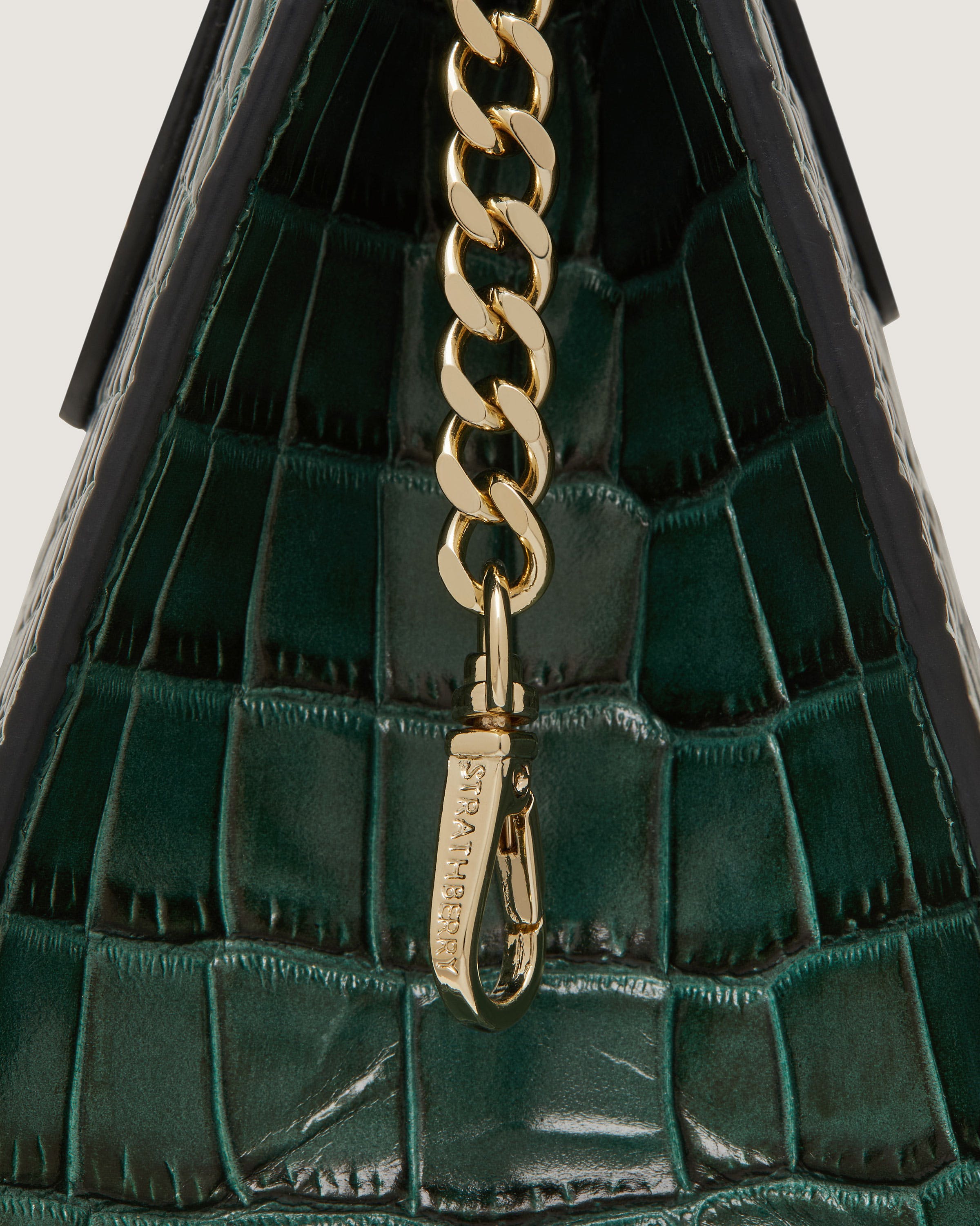 A green handbag with a gold chain hanging from it