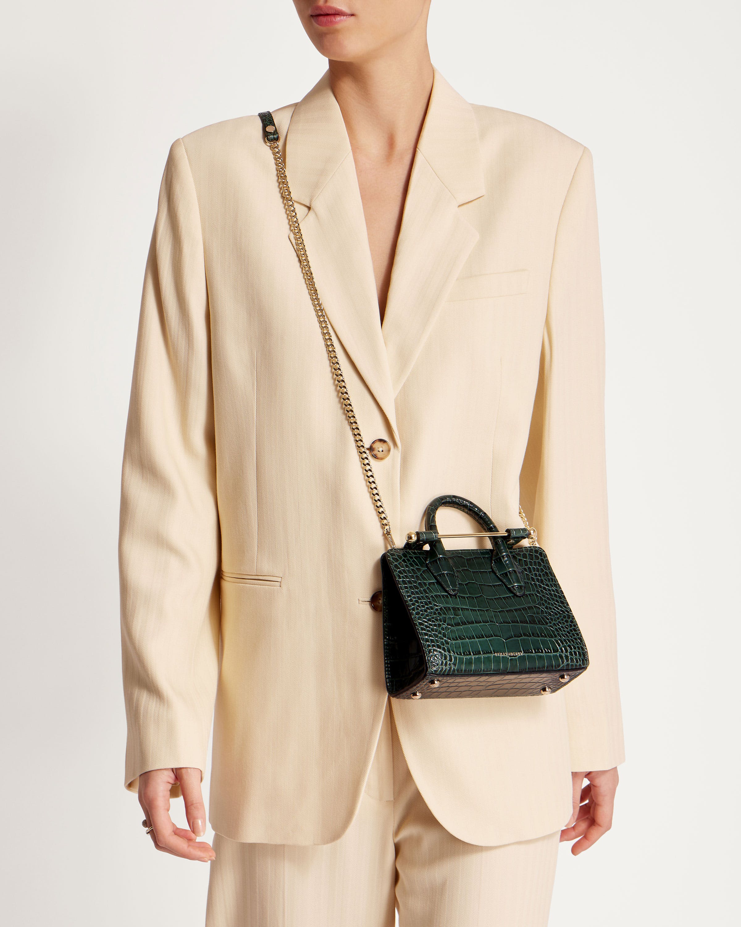 A woman in a suit holding a green purse