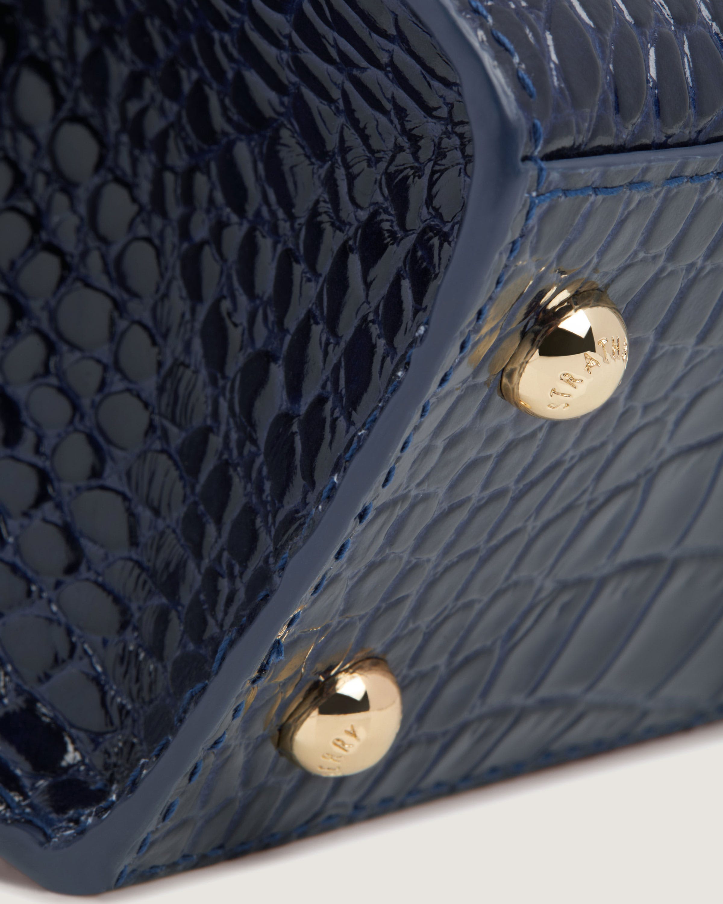 A close up of a blue purse with two gold buttons