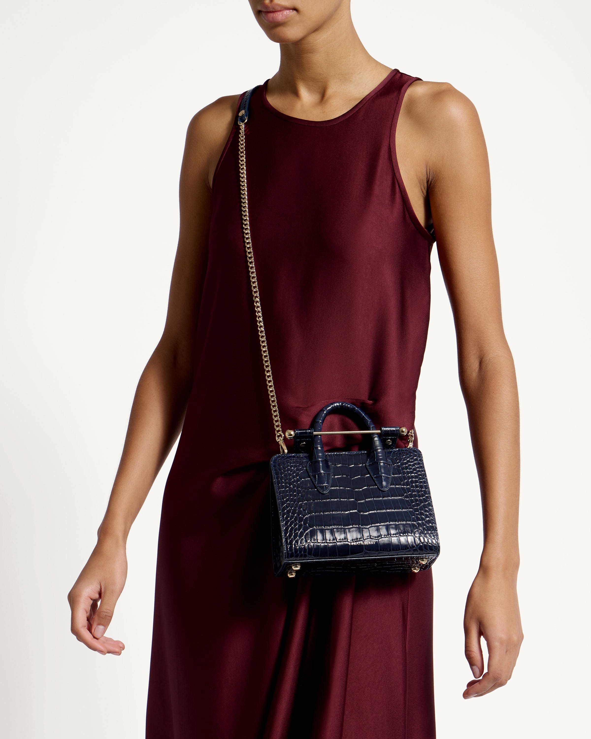 A woman in a maroon dress holding a black purse