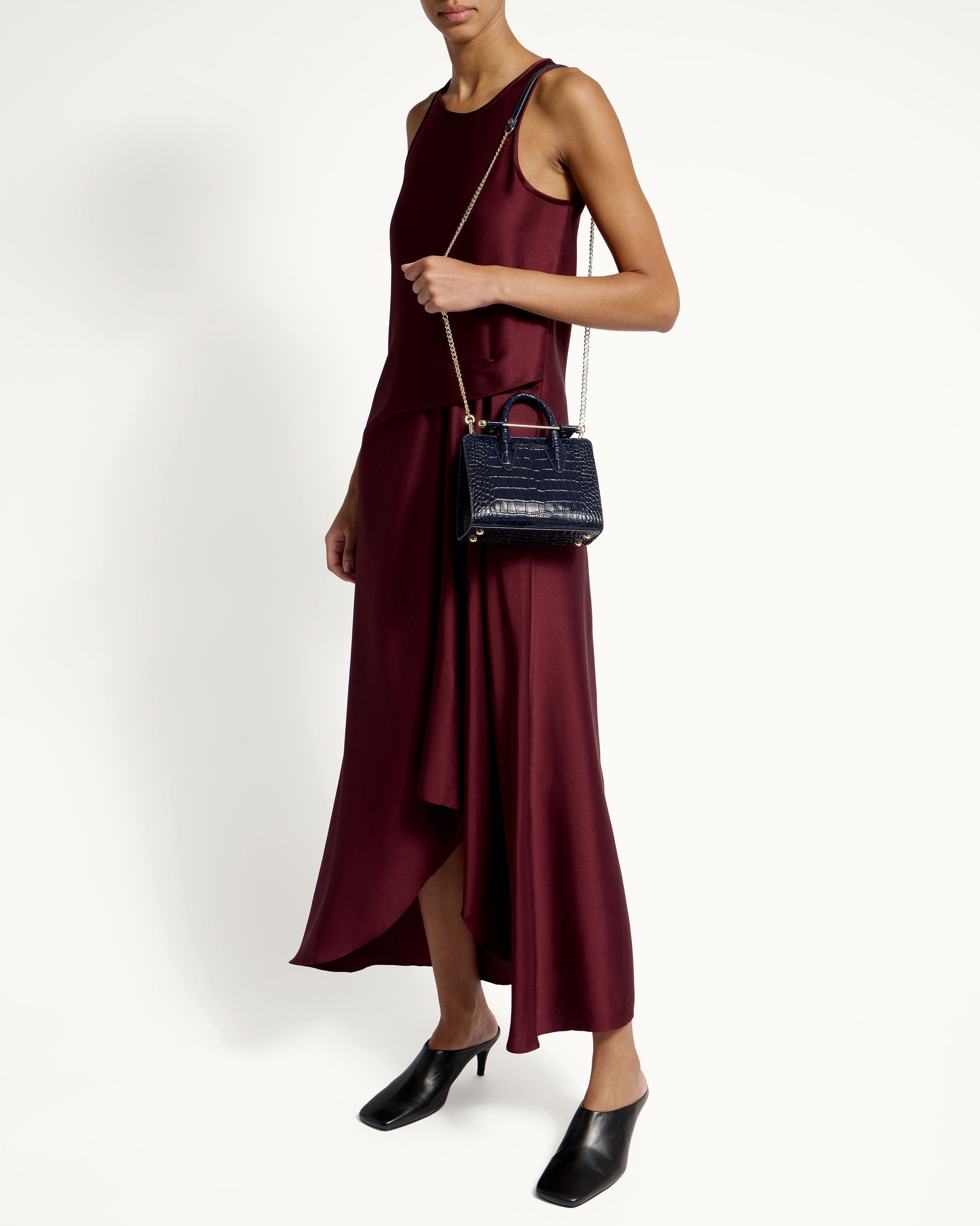 A woman in a maroon dress holding a black purse