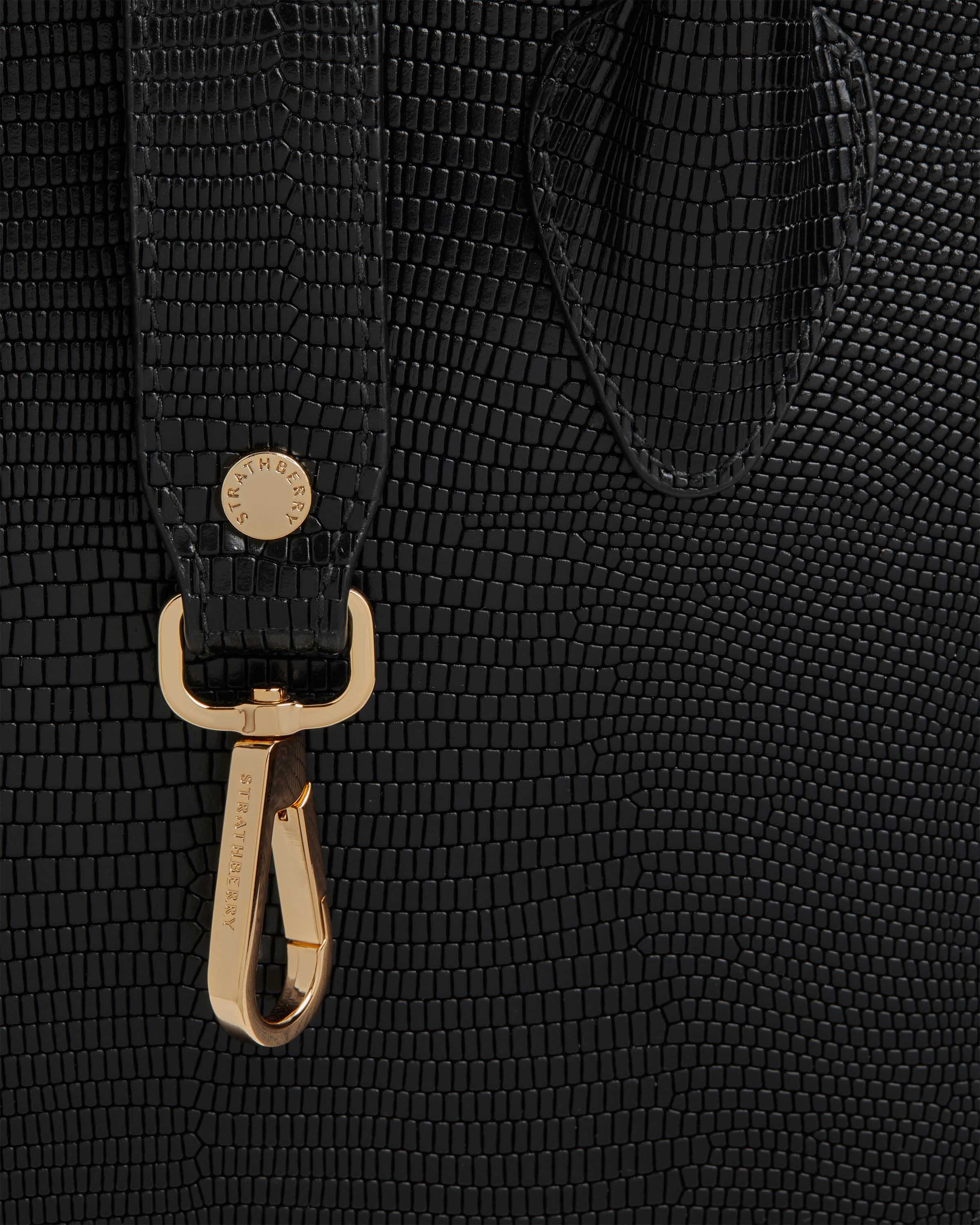 A close up of a black bag with a gold handle