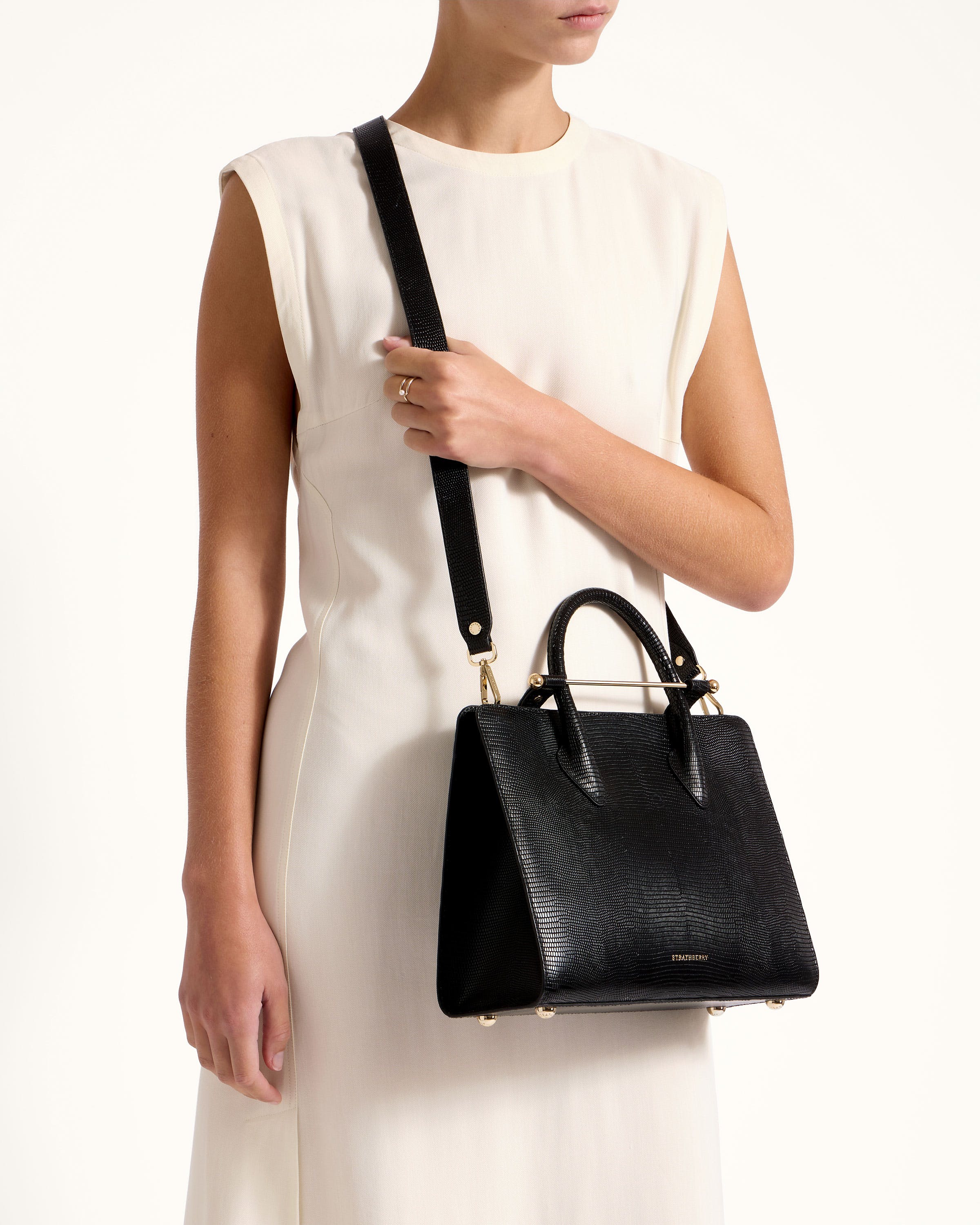 A woman in a white dress holding a black handbag