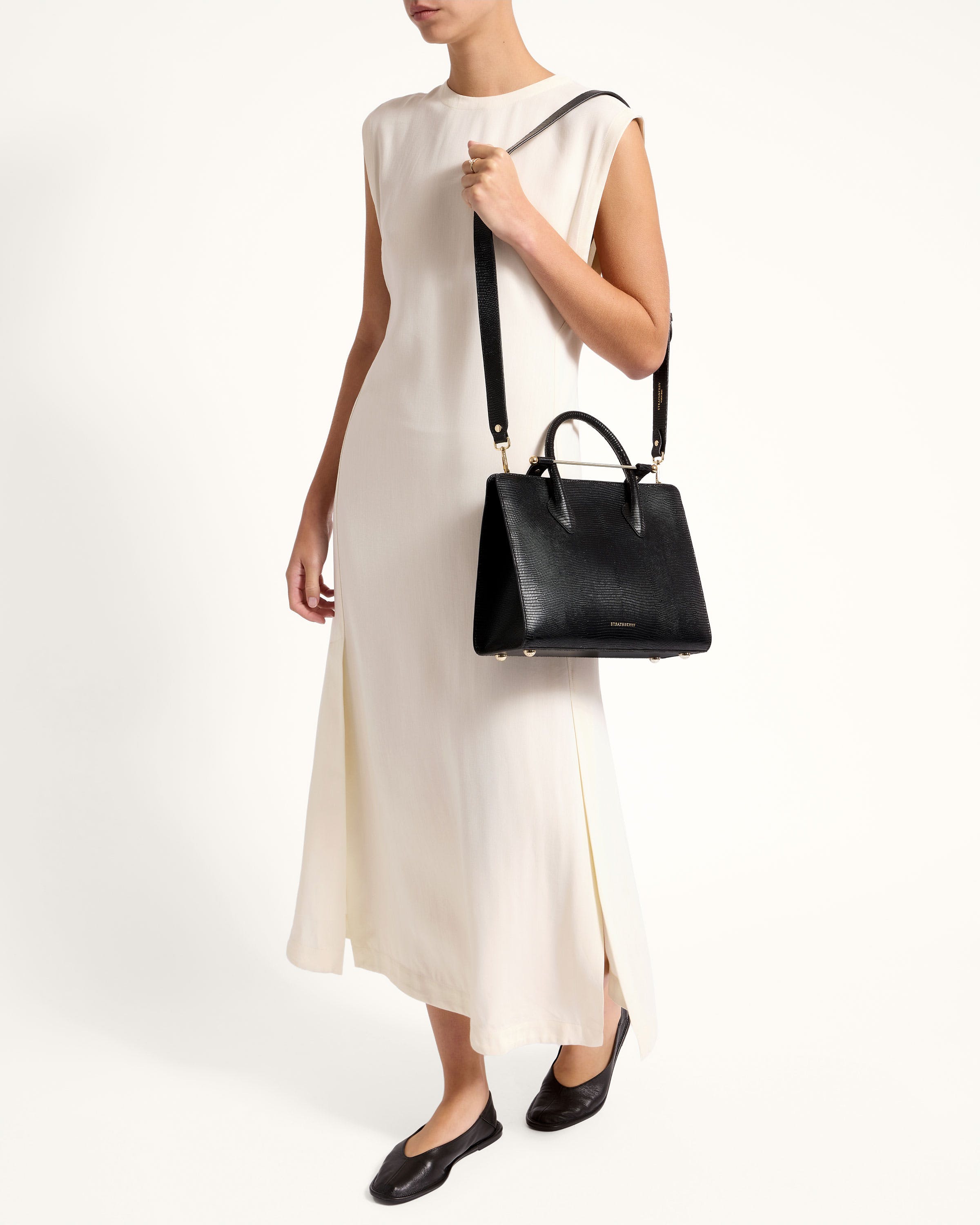 A woman in a white dress holding a black handbag