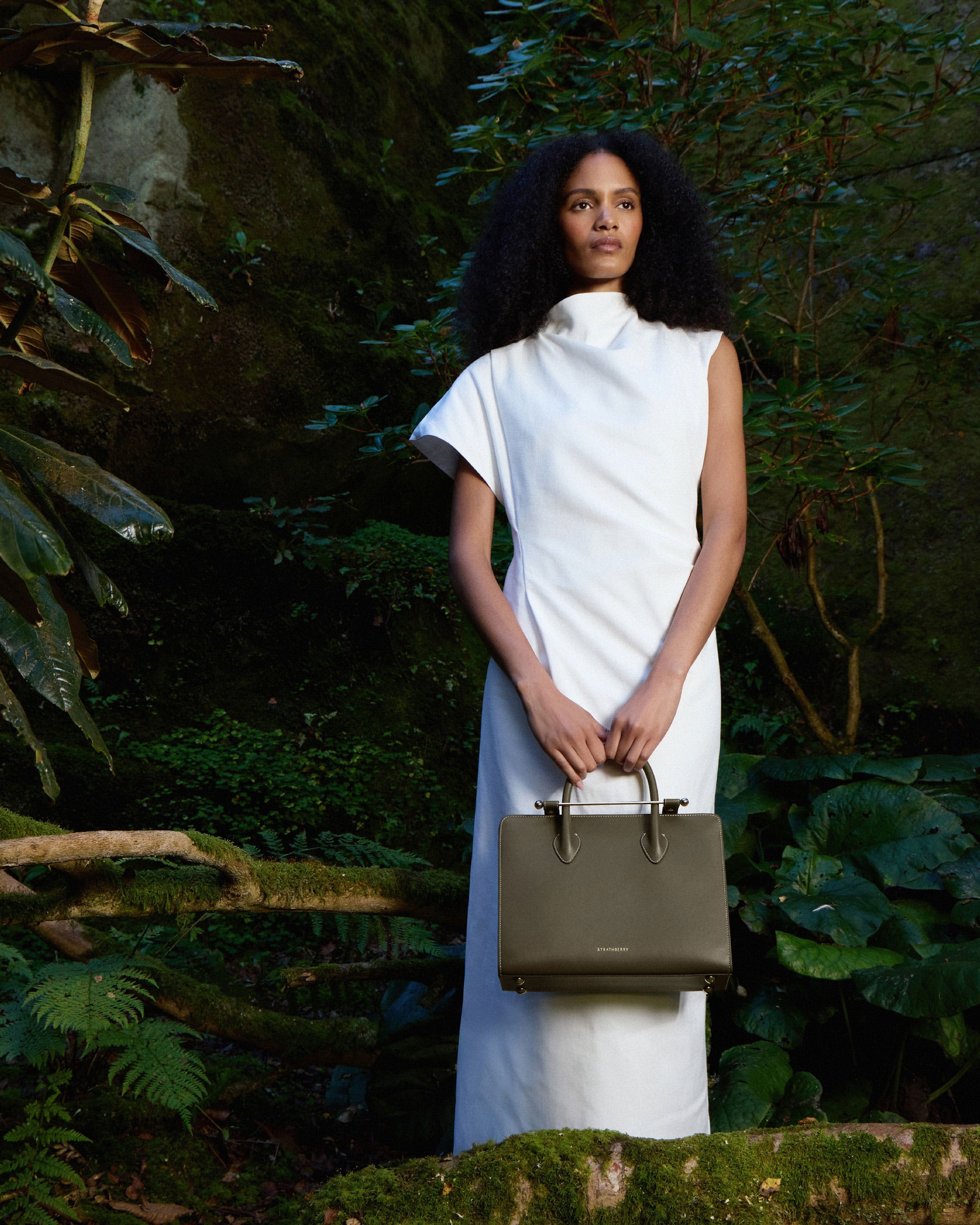 A woman in a white dress holding a brown bag