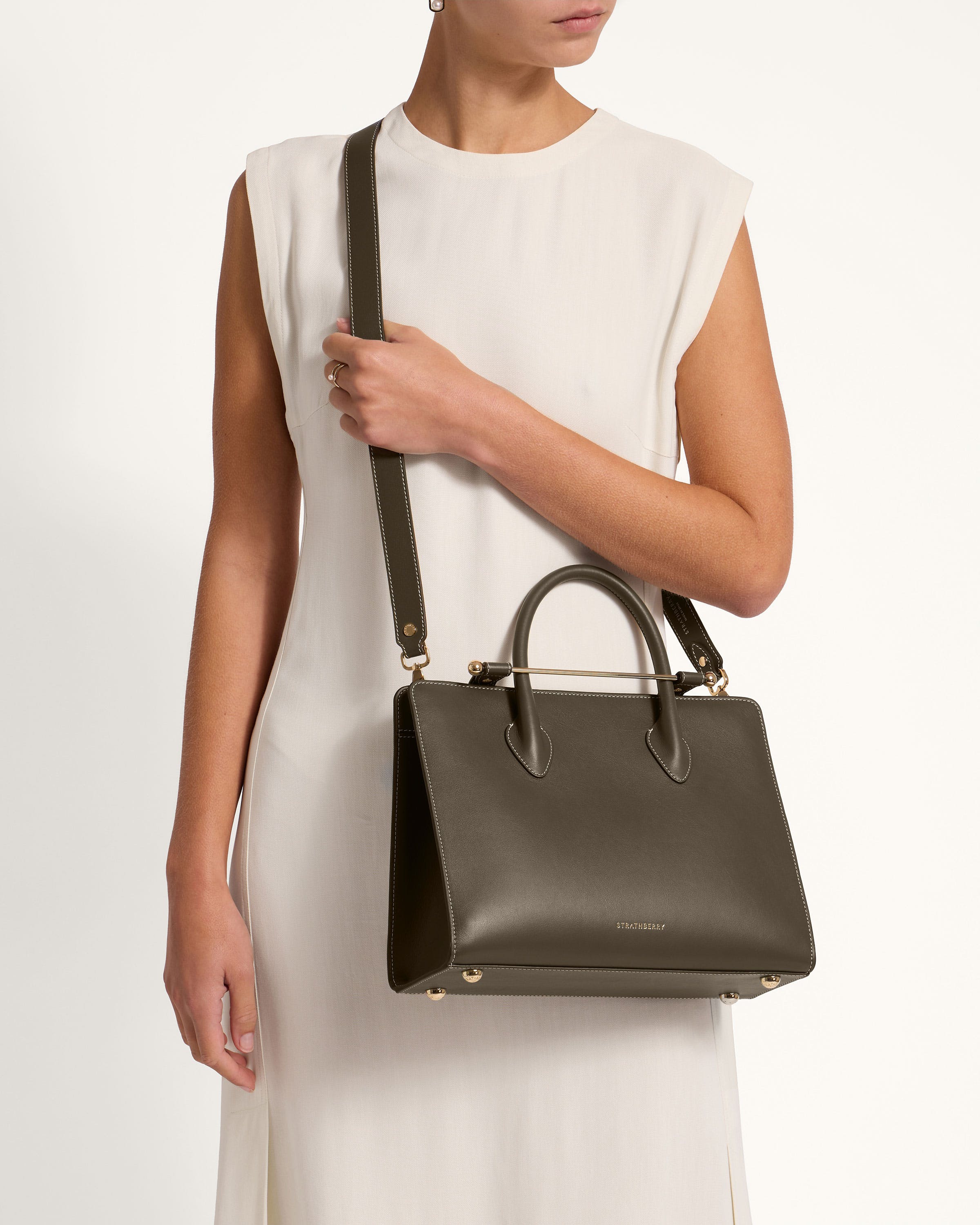 A woman in a white dress holding a black handbag