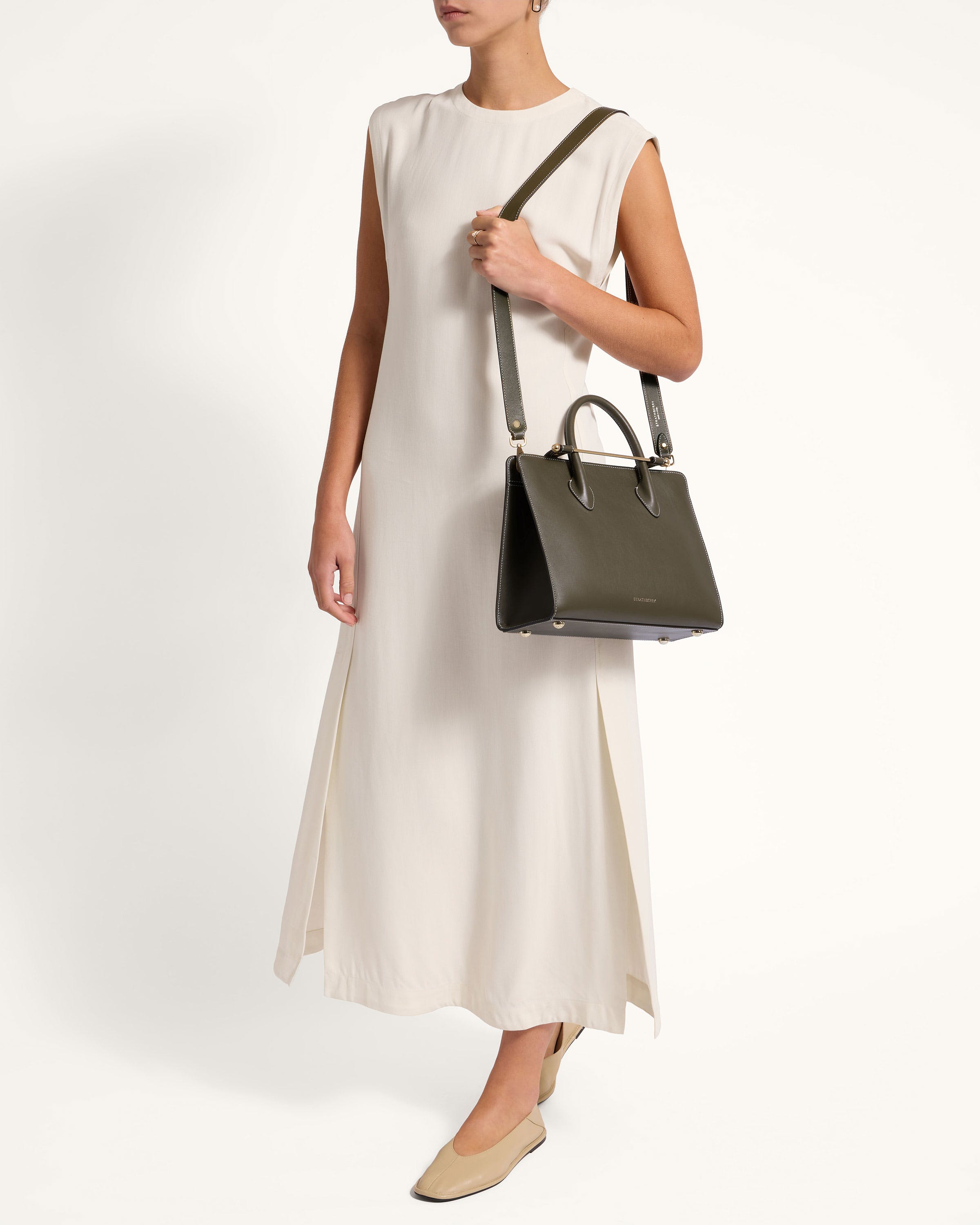 A woman in a white dress holding a black handbag