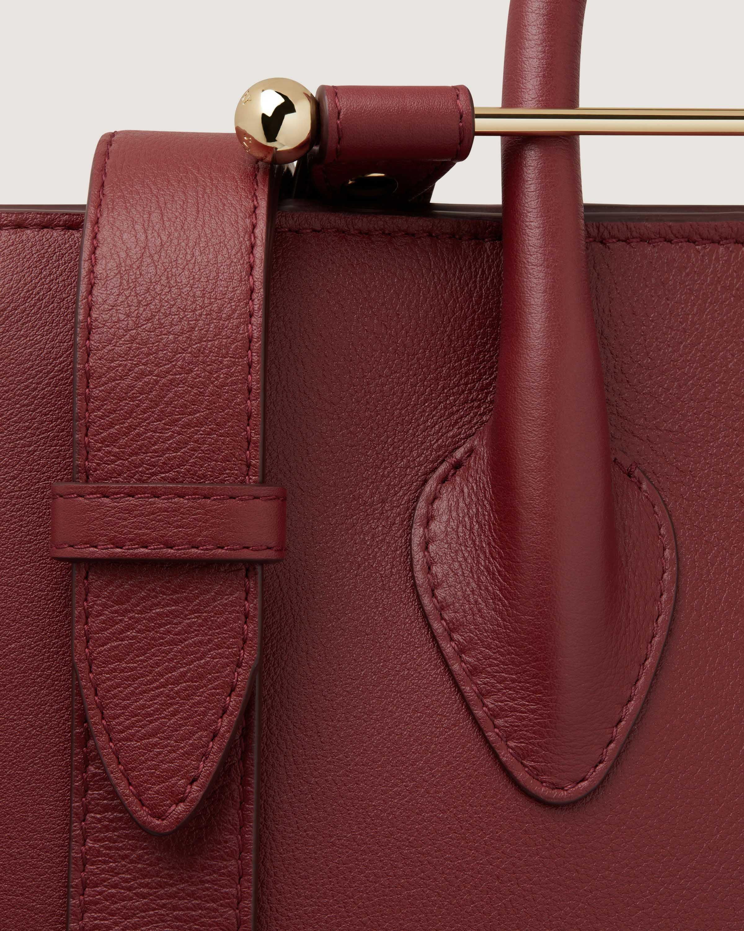 A close up of a red handbag with a gold handle