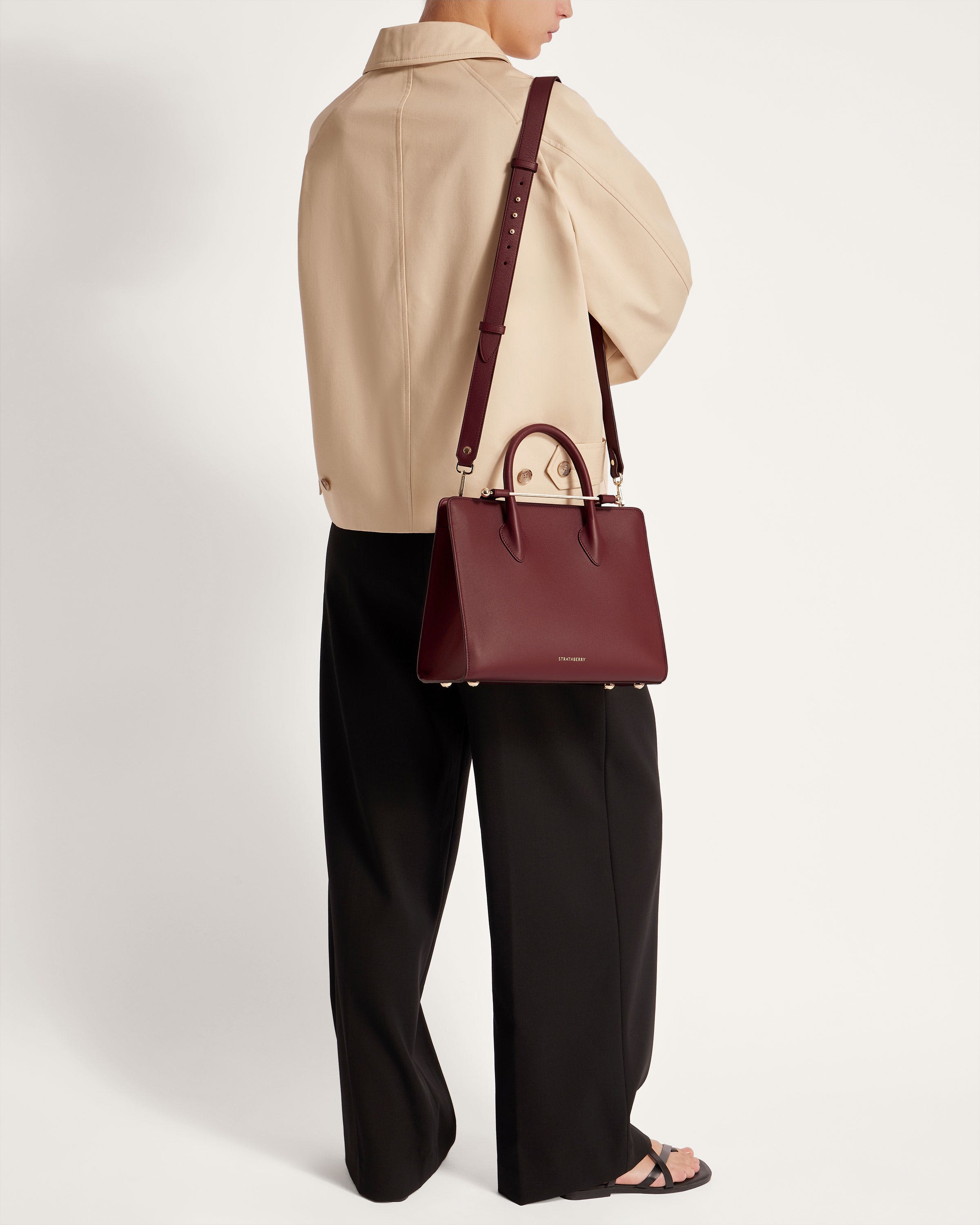 A woman is holding a burgundy handbag