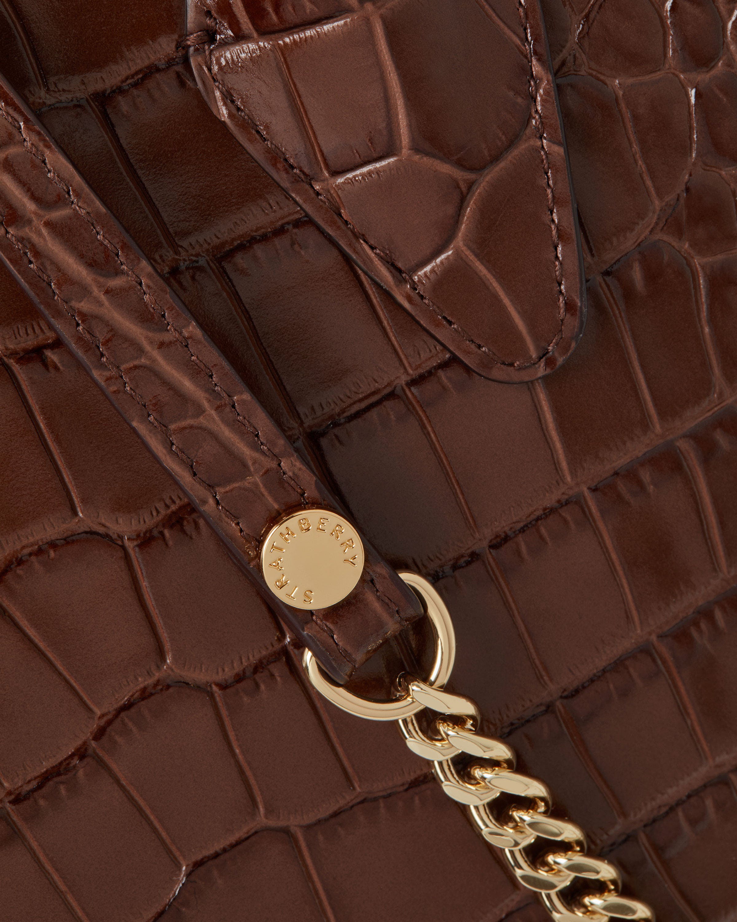 A close up of a brown purse with a gold chain