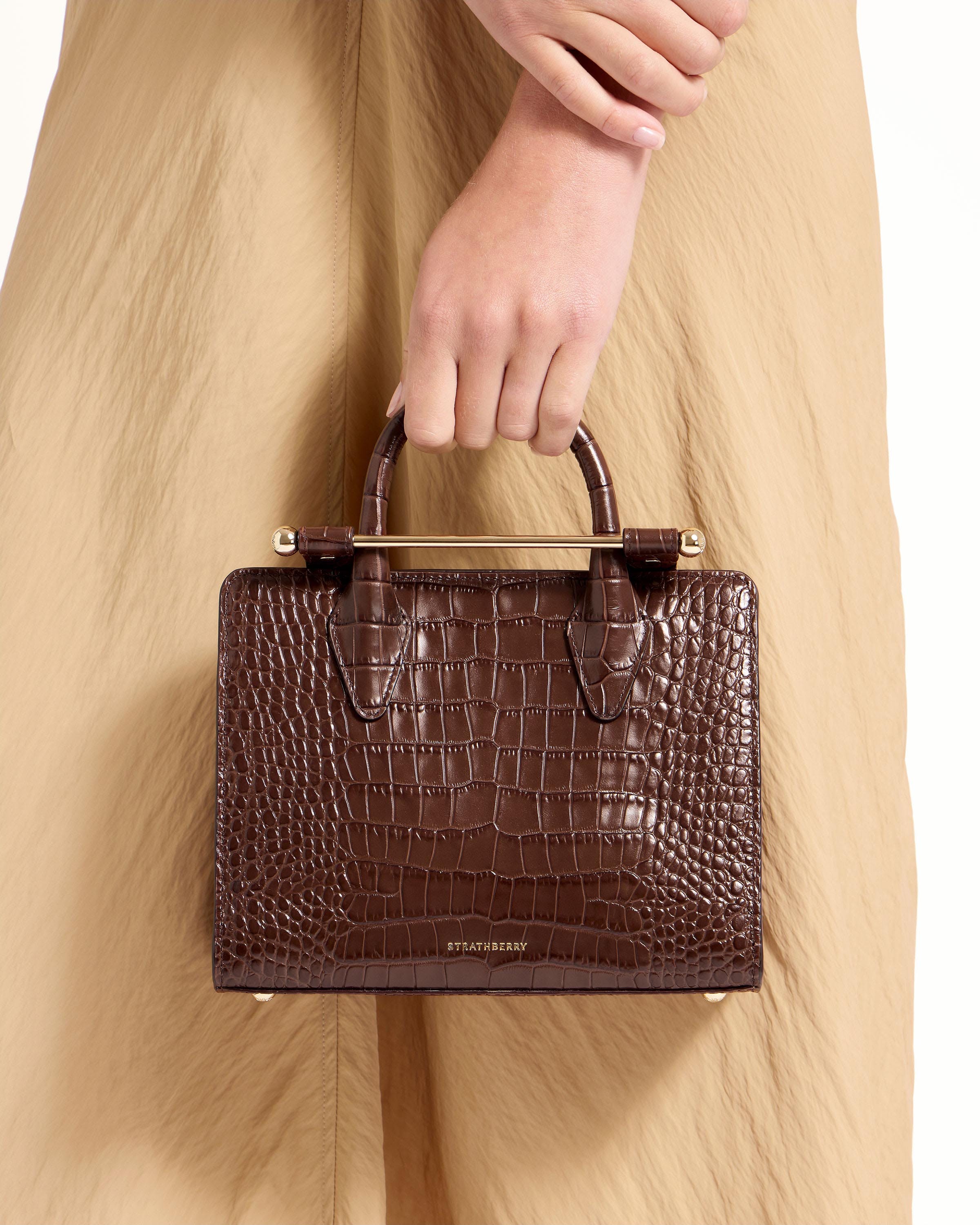 A woman is holding a brown purse in her hand