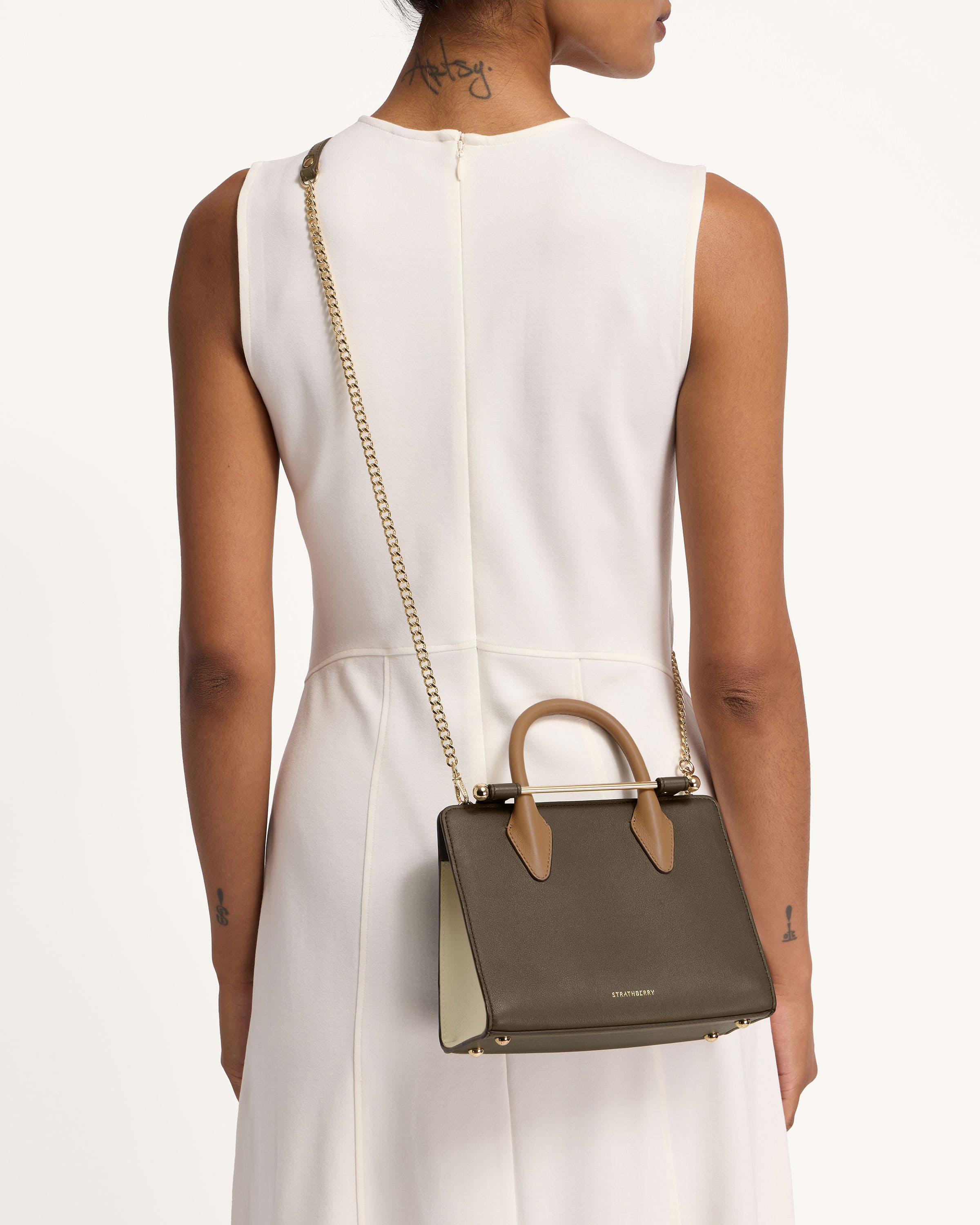 A woman in a white dress holding a brown handbag