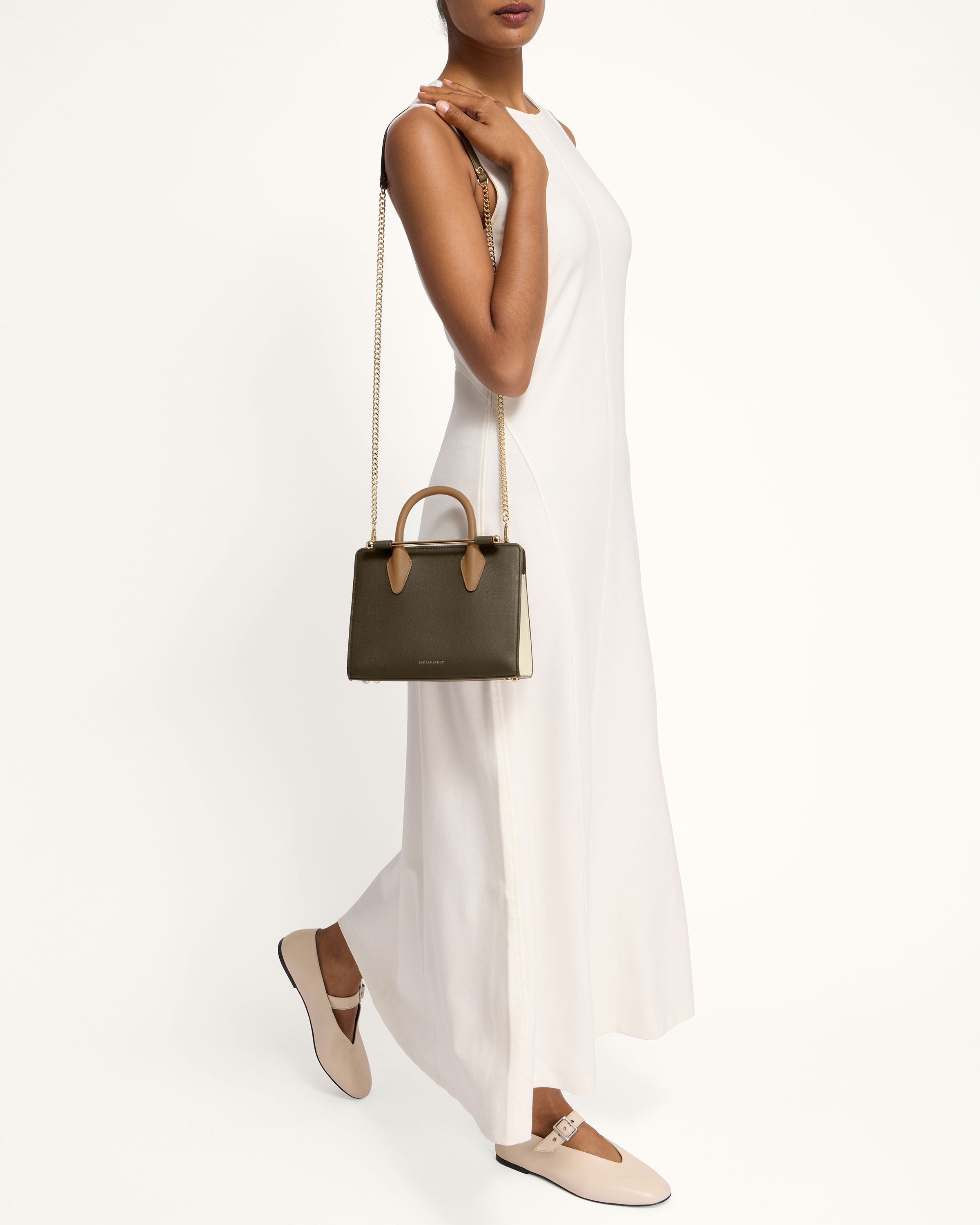 A woman in a white dress holding a brown handbag