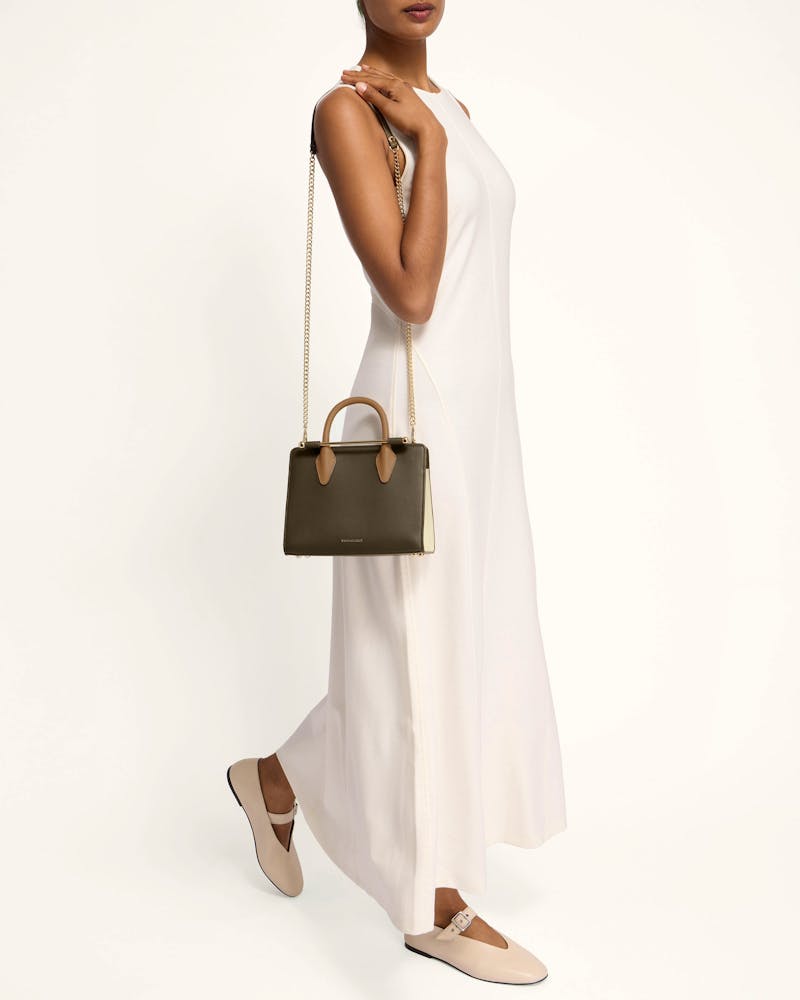 A woman in a white dress holding a brown handbag