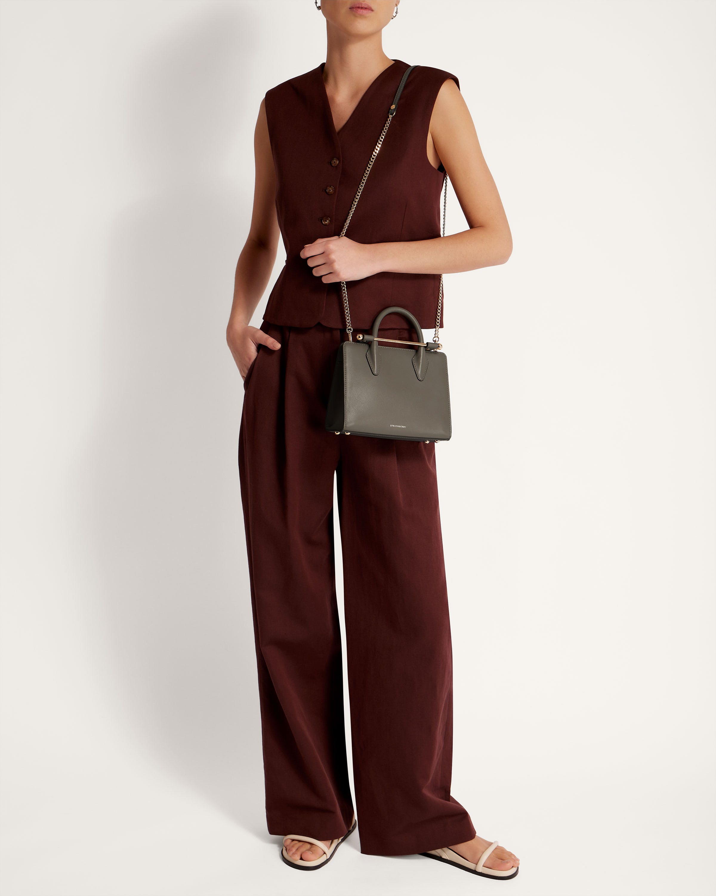 A woman in a brown jumpsuit holding a handbag