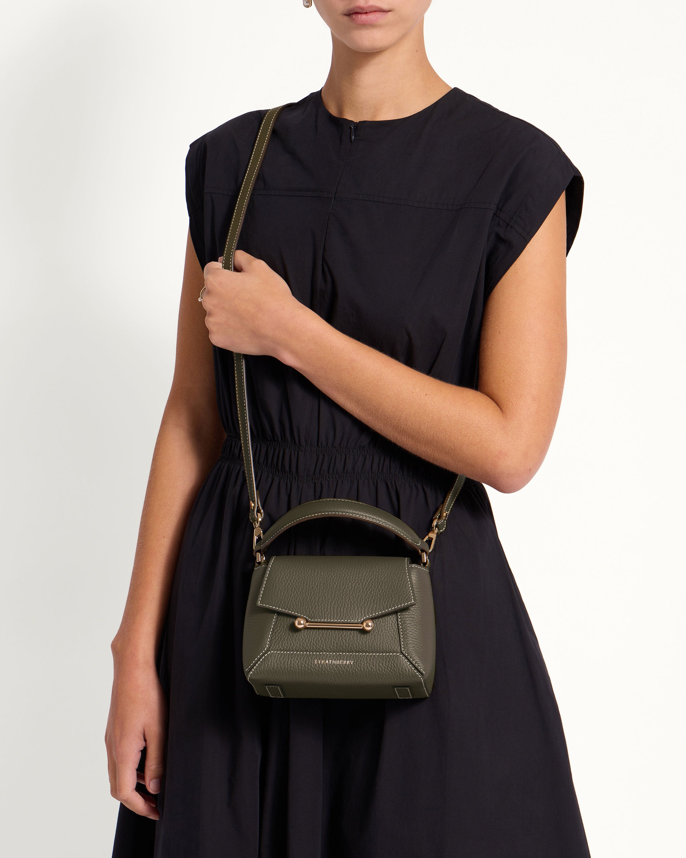 A woman in a black dress holding a green purse